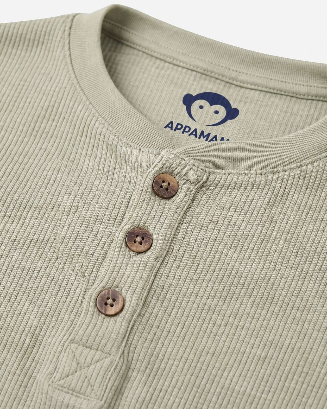 Close-up of a ribbed green shirt with brown buttons and Appama logo.