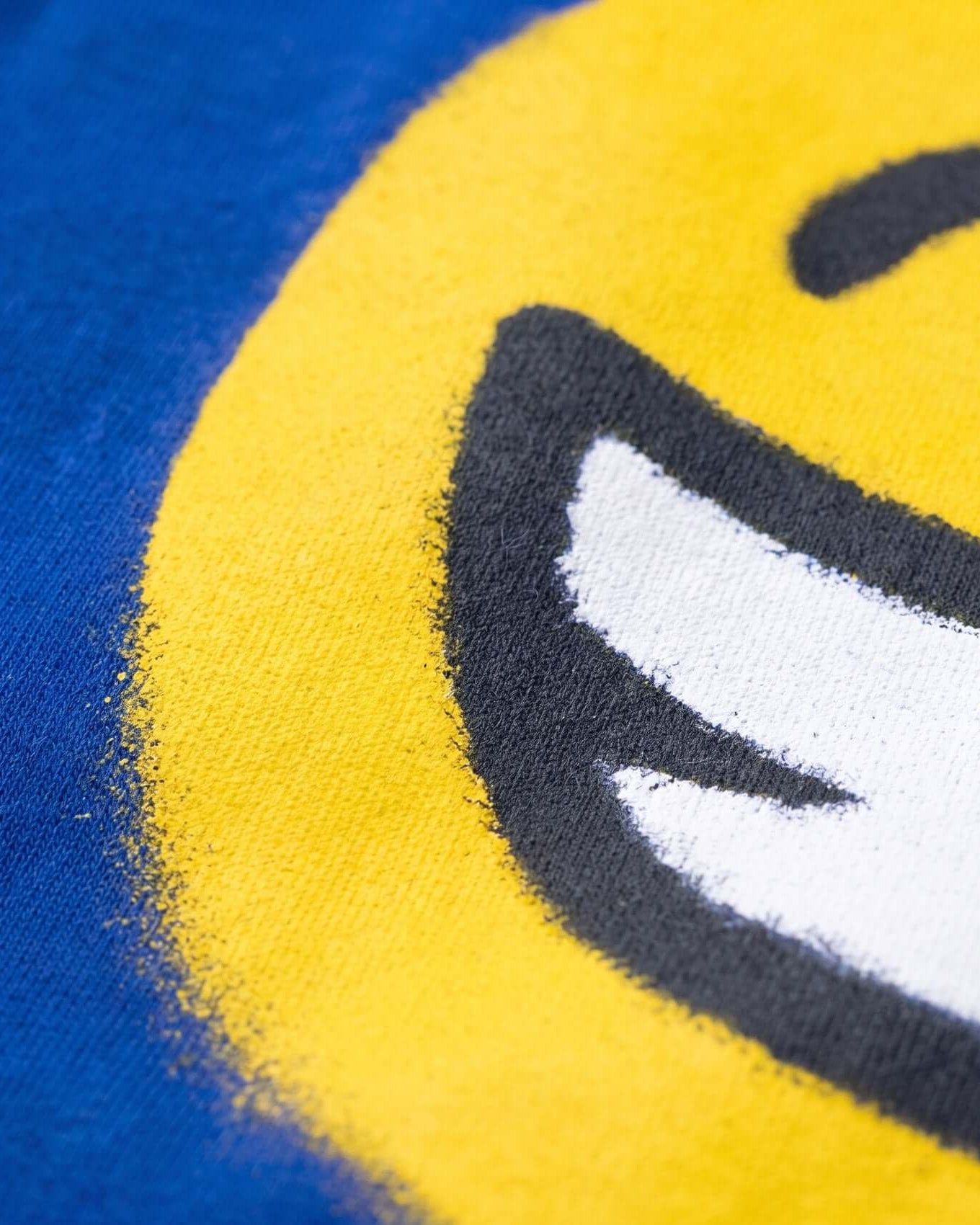 Close-up of a smiley face design on fabric with blue and yellow background