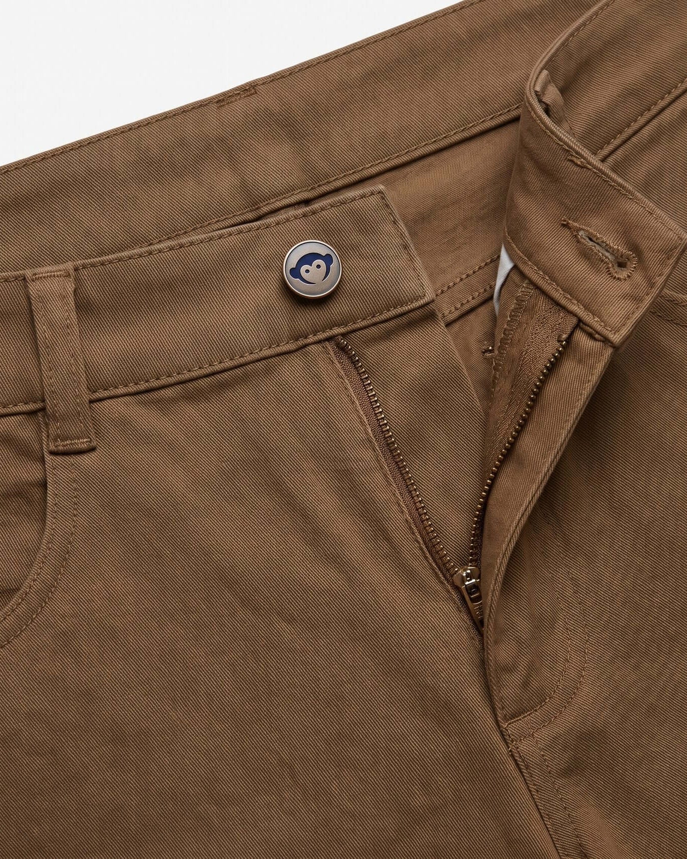 Close-up of brown pants with a button and zipper detail on a white background