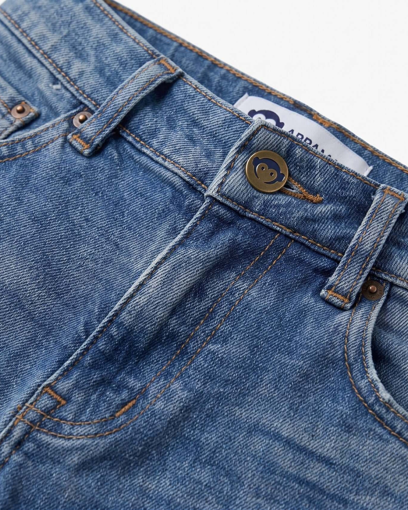 Close-up of blue denim jeans with a brand label on a white background