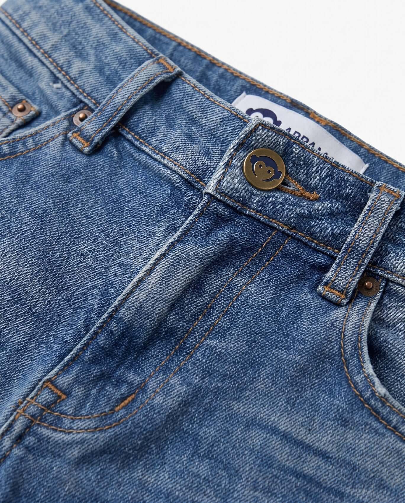Close-up of blue denim jeans with a brand label on a white background