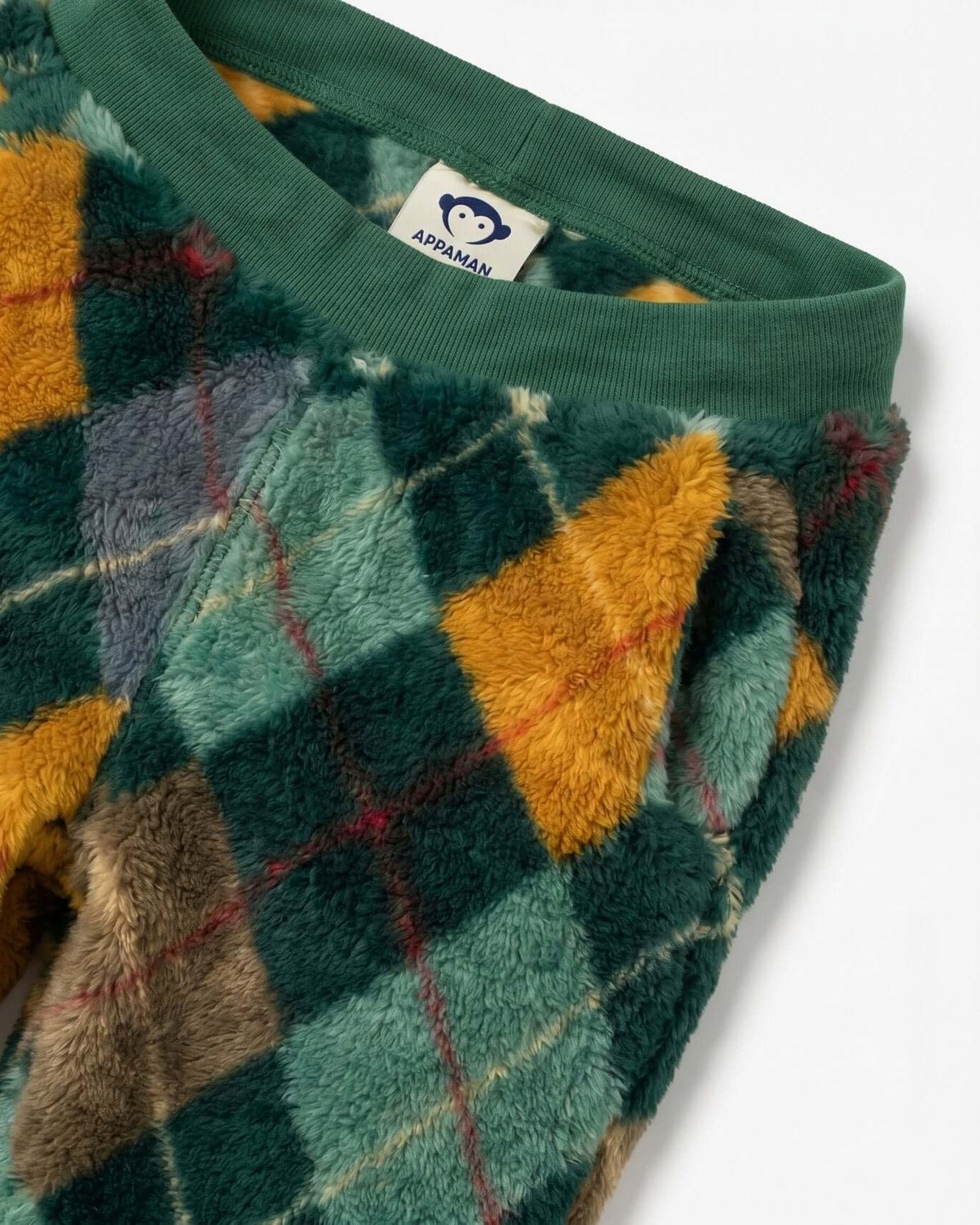 Close-up of a green fleece fabric with colorful geometric pattern and a brand label.