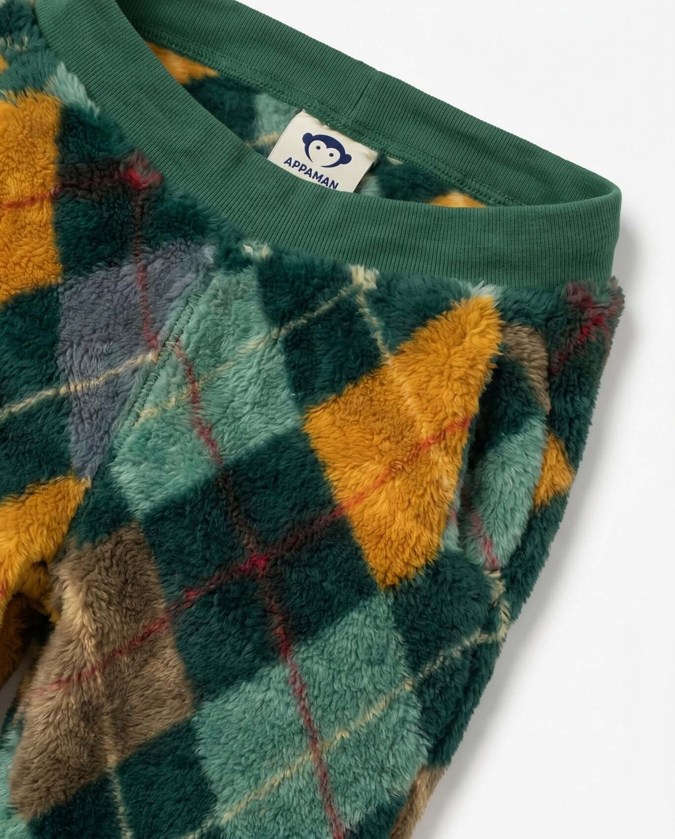 Close-up of a green fleece fabric with colorful geometric pattern and a brand label.