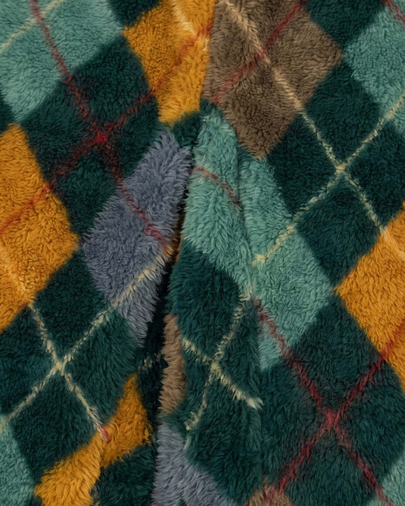Close-up of a textured fabric with a diamond pattern in green, orange, and brown.