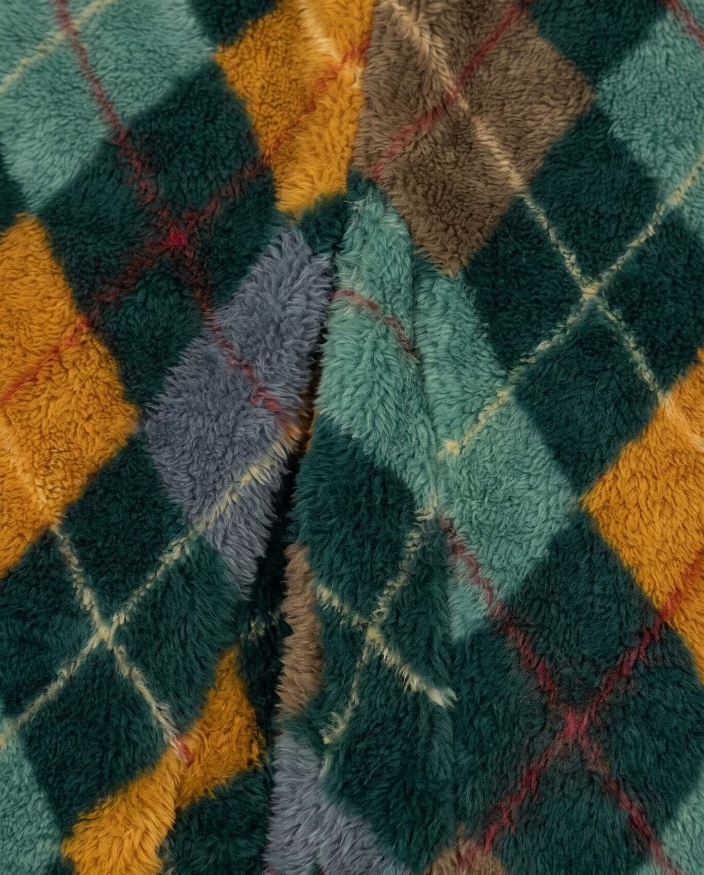 Close-up of a textured fabric with a diamond pattern in green, orange, and brown.