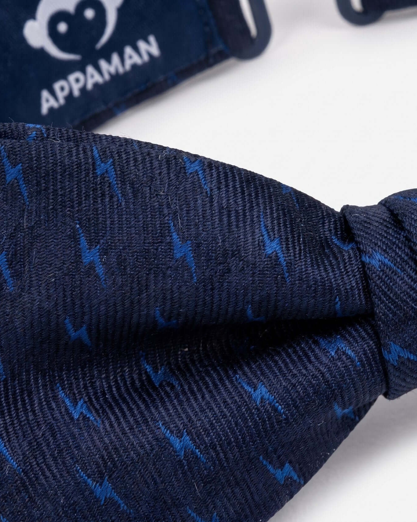 Close-up of navy blue fabric with blue patterns, branded 'Appaman' in the background.