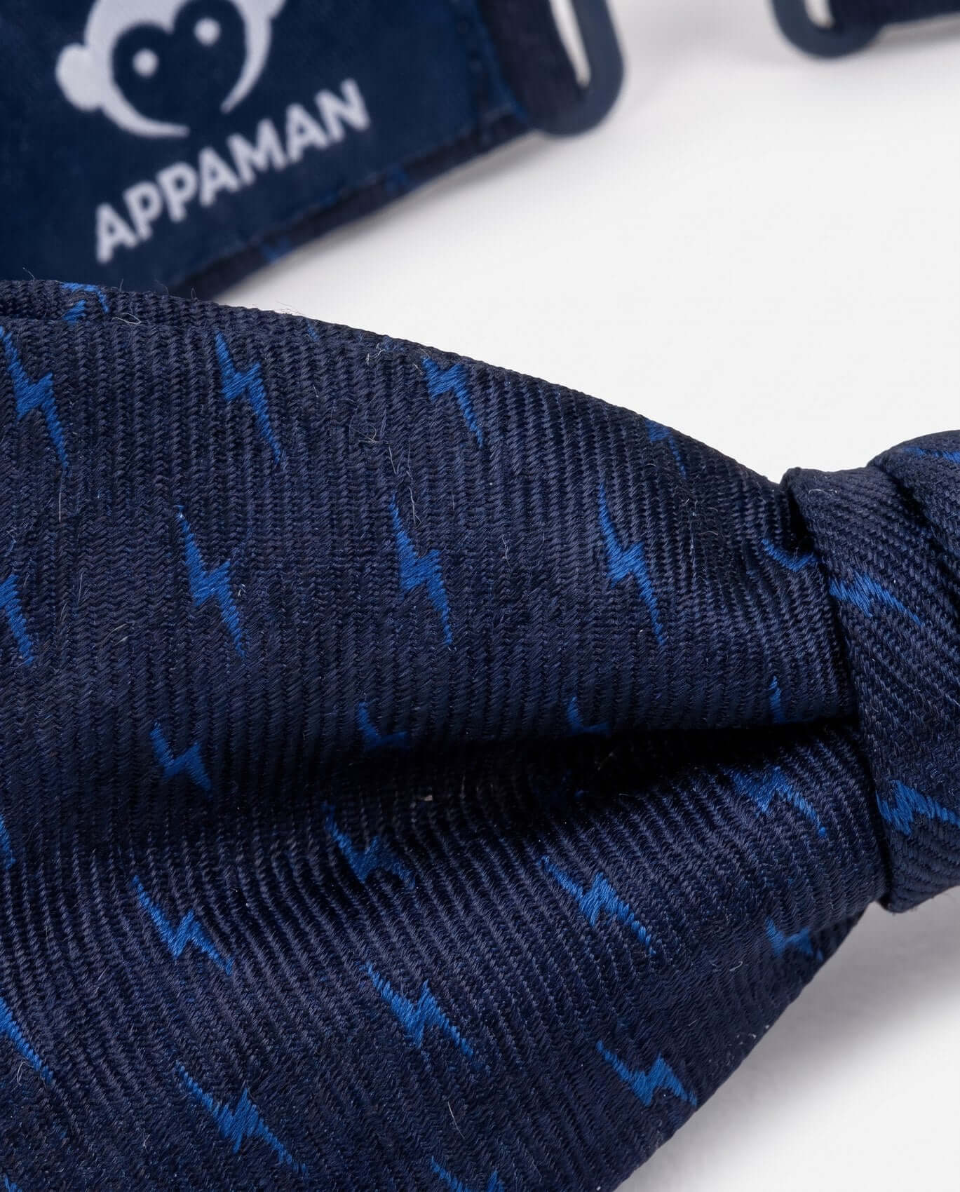 Close-up of navy blue fabric with blue patterns, branded 'Appaman' in the background.