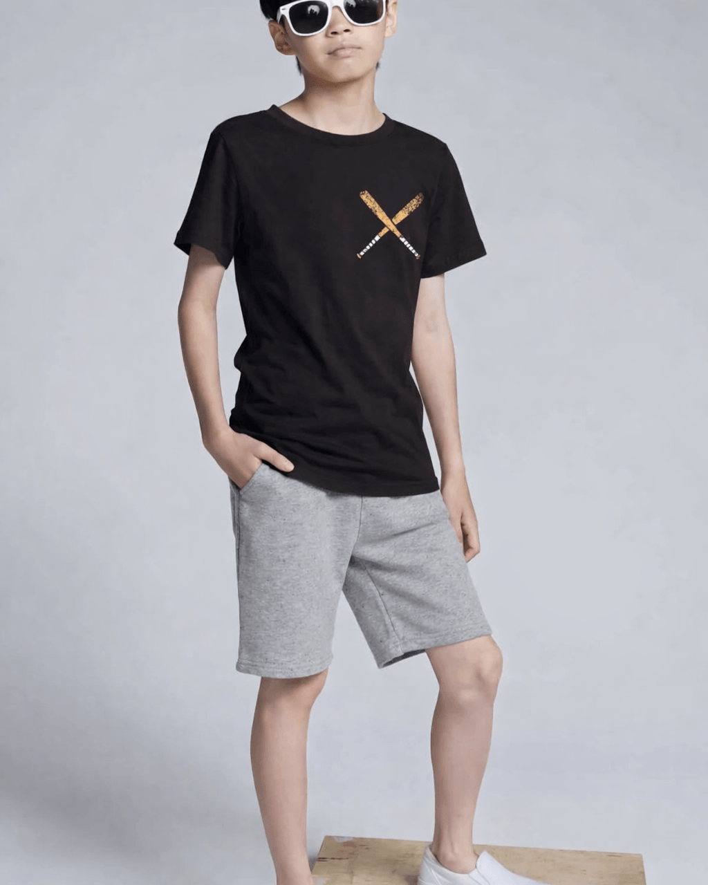 Person wearing a black t-shirt with a logo and gray shorts on a white background