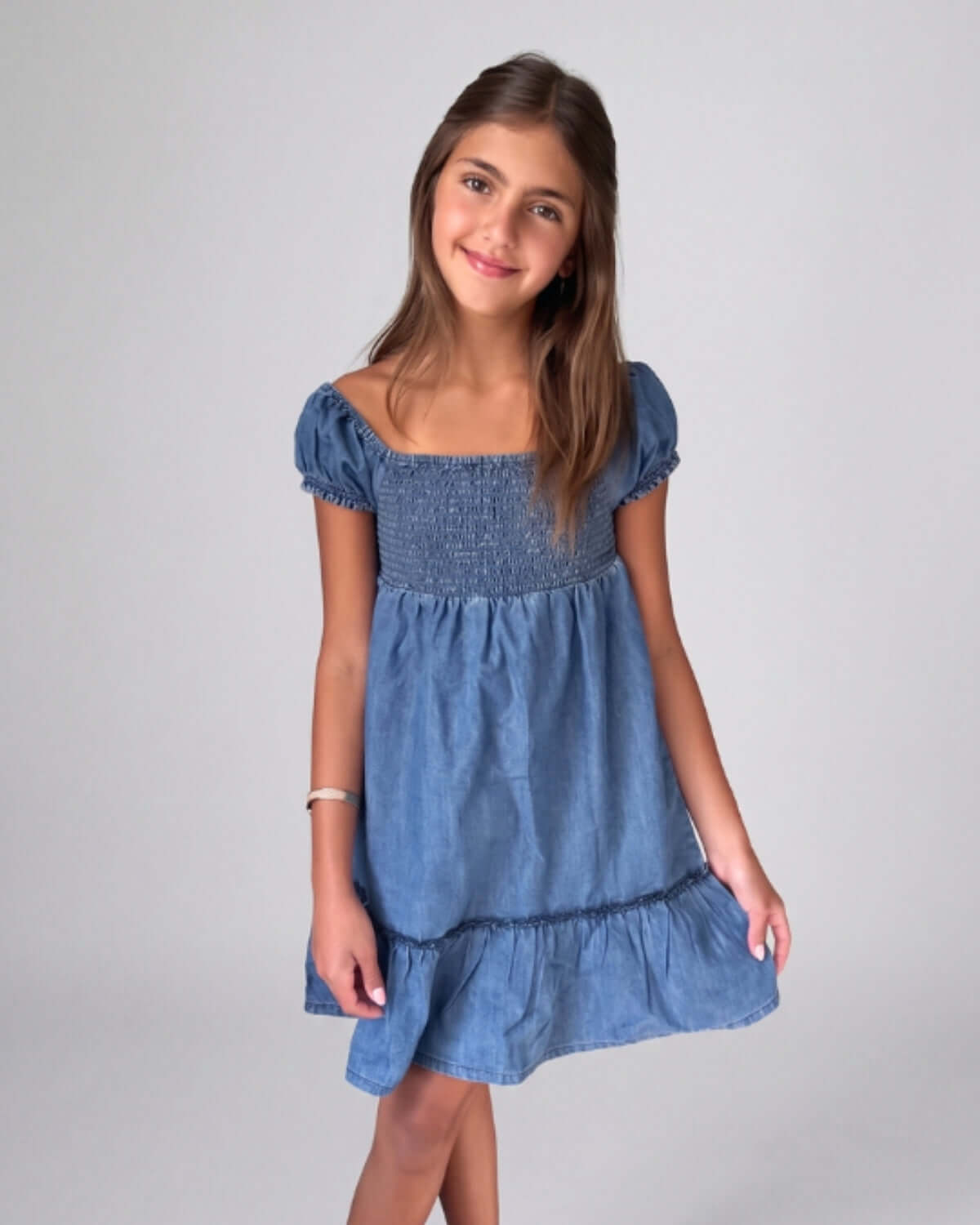 Young girl wearing a blue dress against a plain background