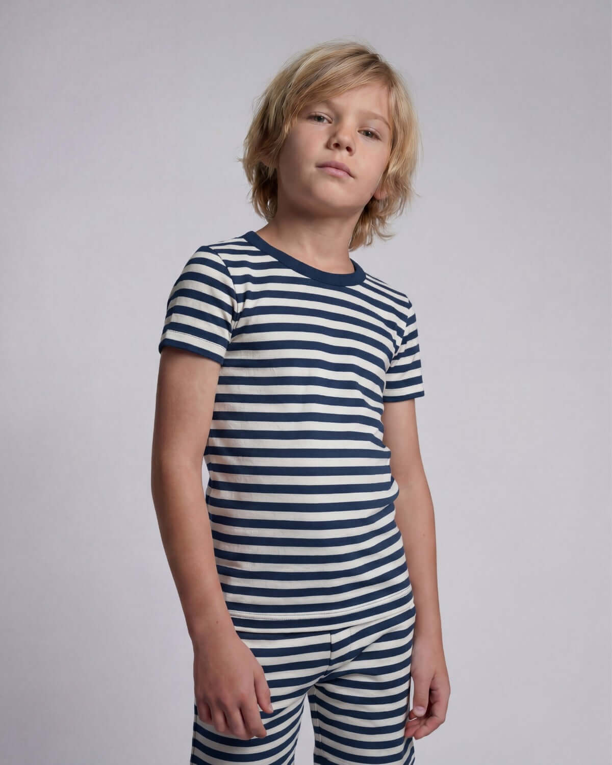 Child wearing a navy and white striped outfit on a plain background