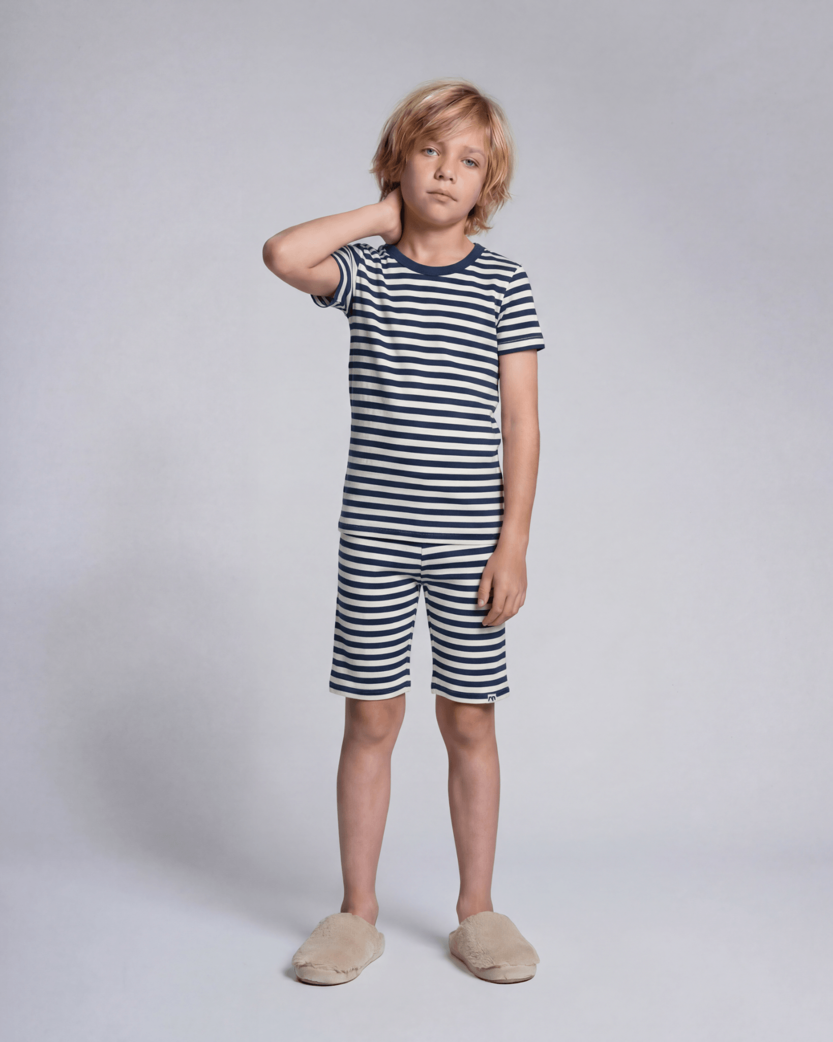 Child wearing a navy and white striped outfit on a plain background