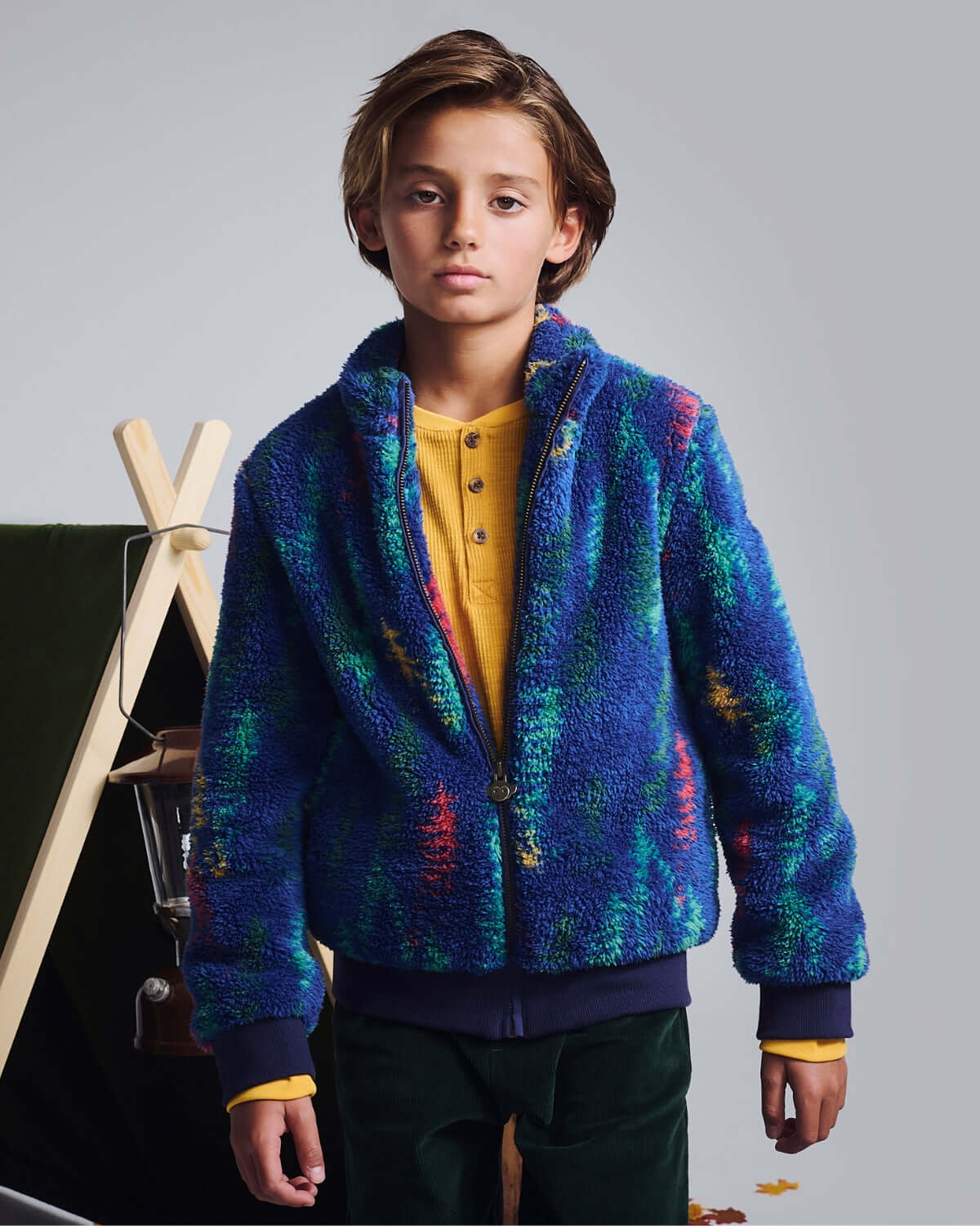 Child wearing a colorful fleece jacket against a neutral background