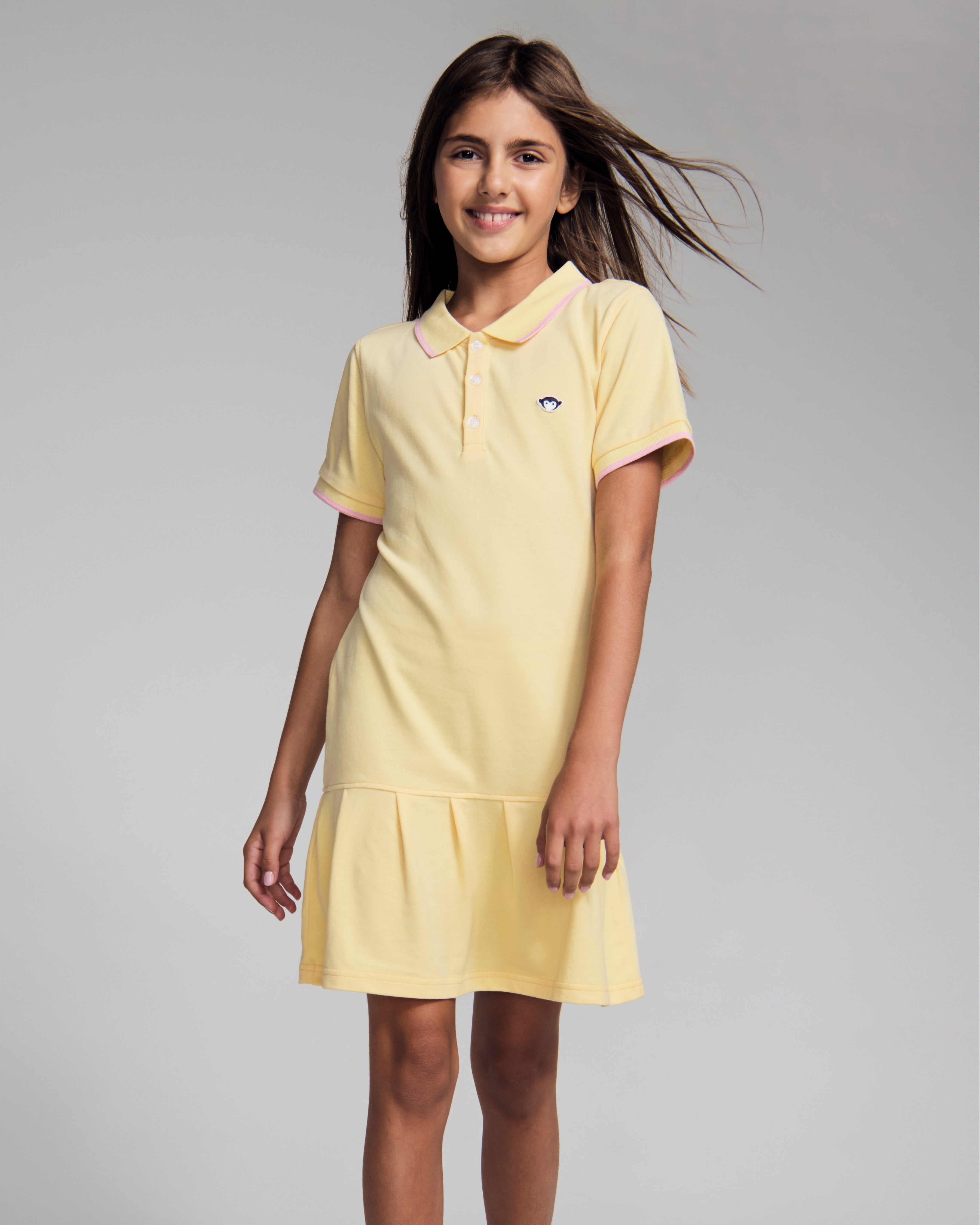 Girl wearing the Buttercup Polo Pleated Dress with short sleeves and pleated skirt.