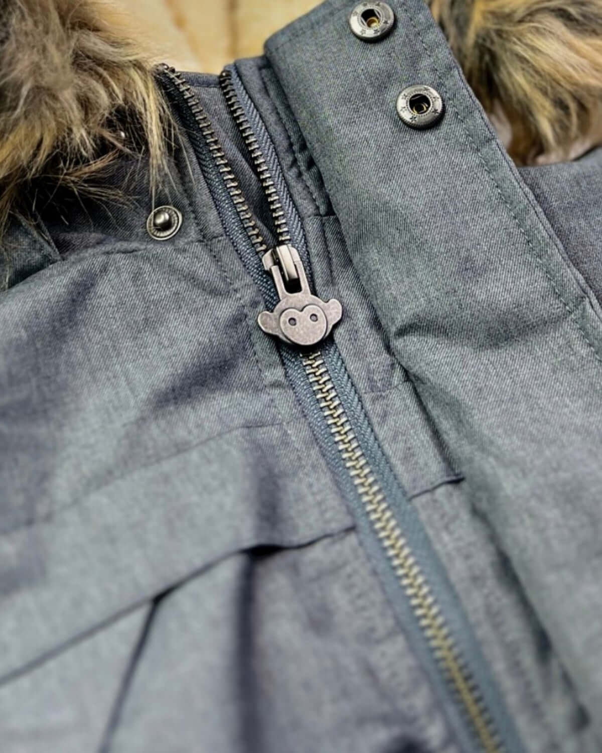 Close-up of the zipper and fur trim on the Grey Denali Down Coat, showcasing its detailed design and rugged exterior.