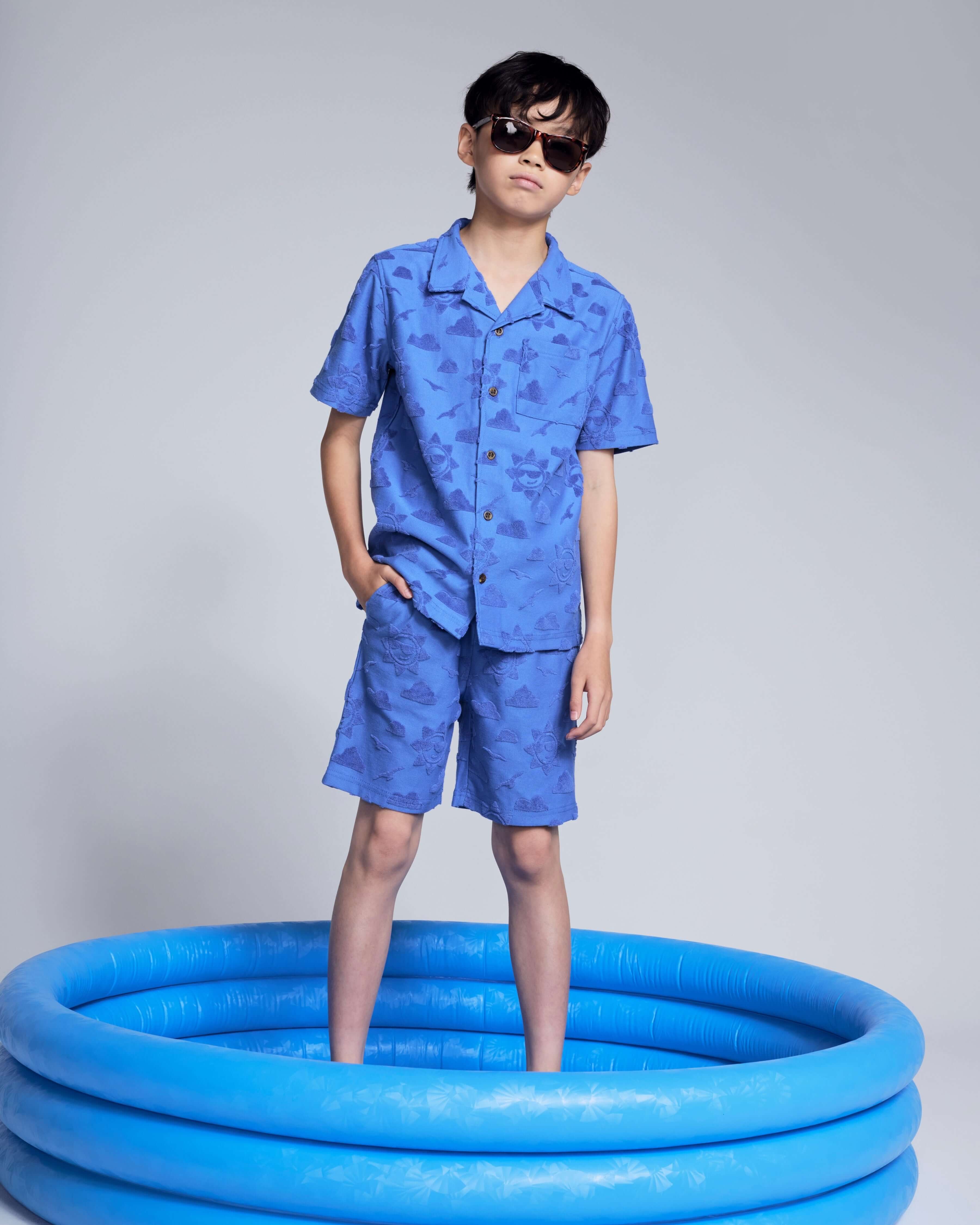 Cobalt Blue Terry Resort Short worn by a child in sunglasses, standing in a blue inflatable pool.