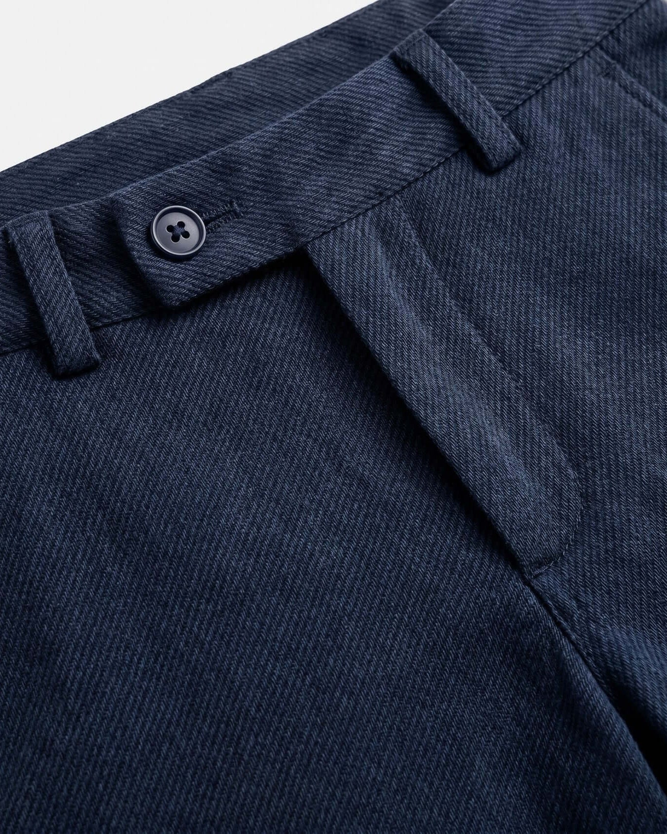Close-up of a blue fabric with a button detail on a light gray background