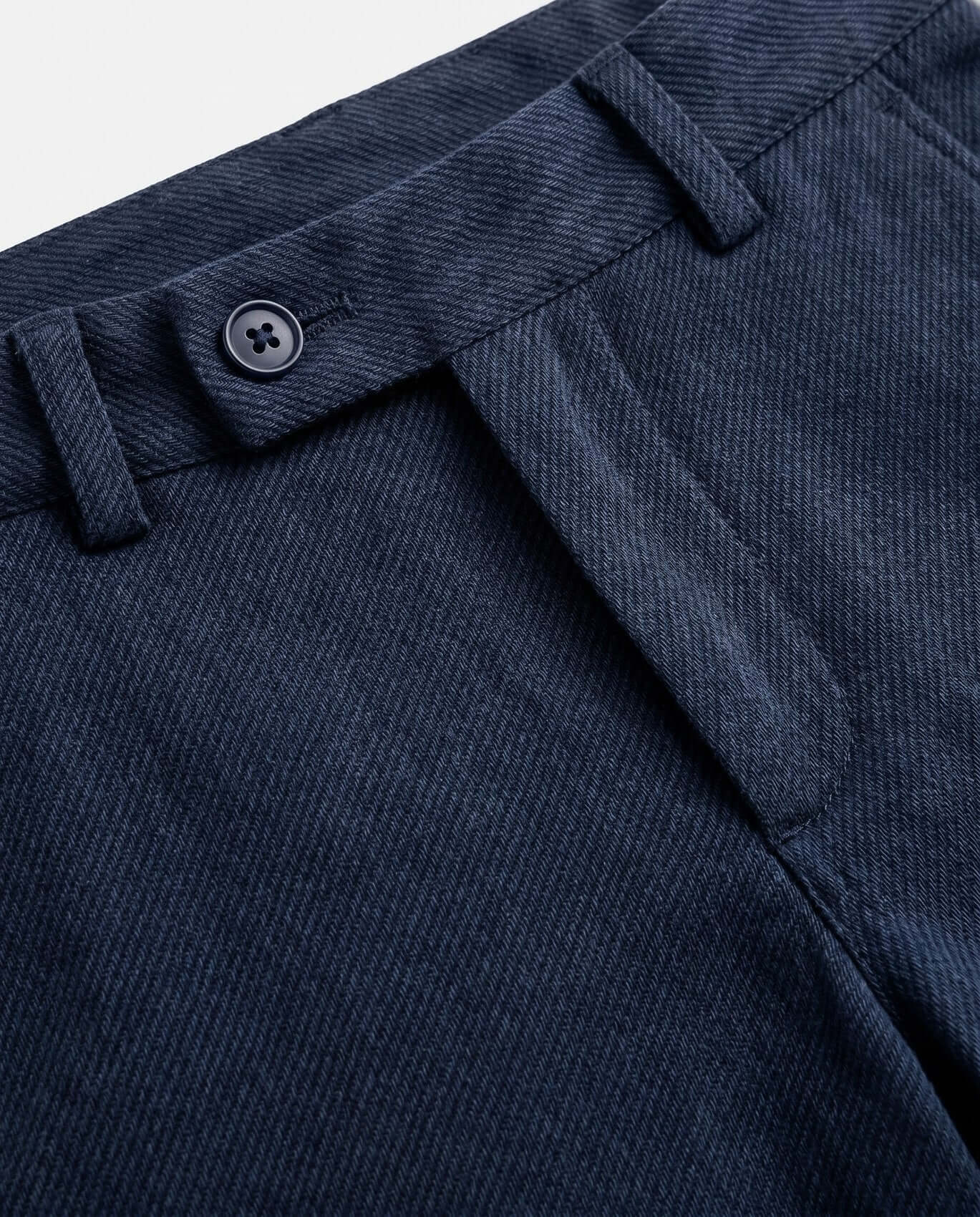 Close-up of a blue fabric with a button detail on a light gray background