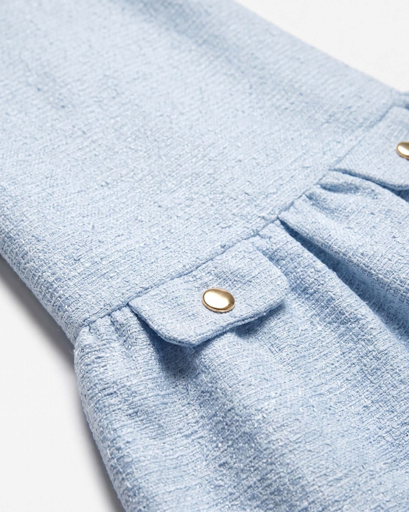 Close-up of a light blue fabric with a button on a white background