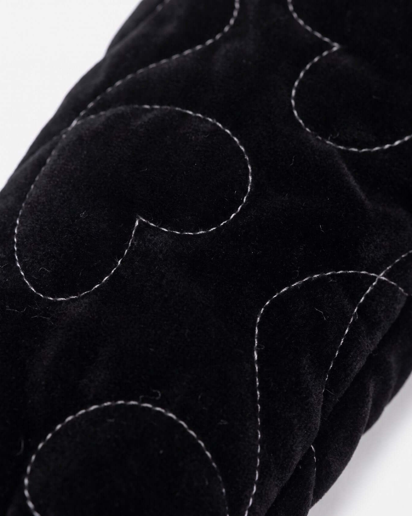 Close-up of black fabric with white stitching on a white background