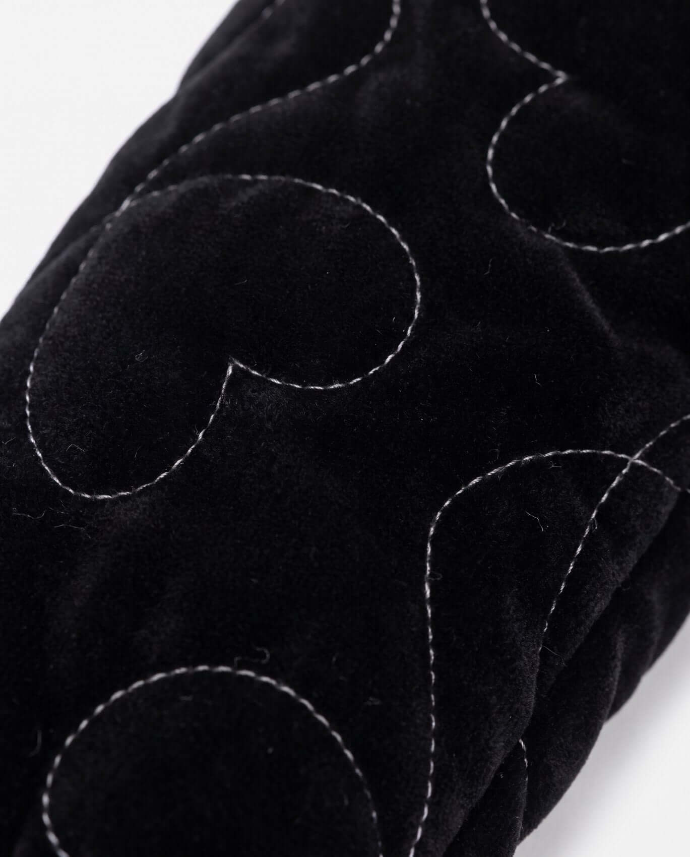 Close-up of black fabric with white stitching on a white background