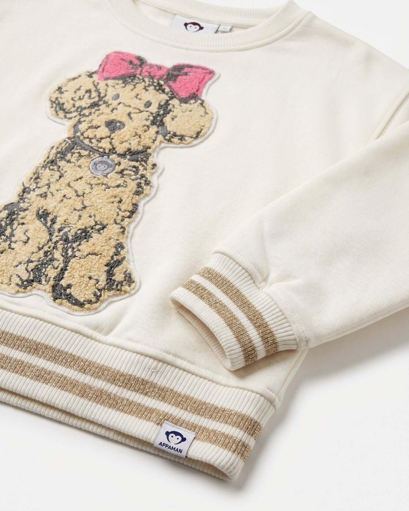 White sweater with teddy bear design and pink bow on a white background
