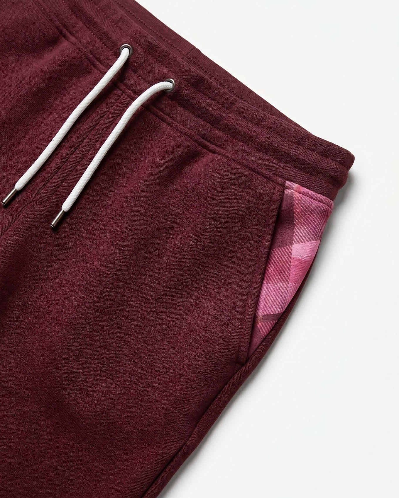 Maroon sweatpants with plaid lining on a white background
