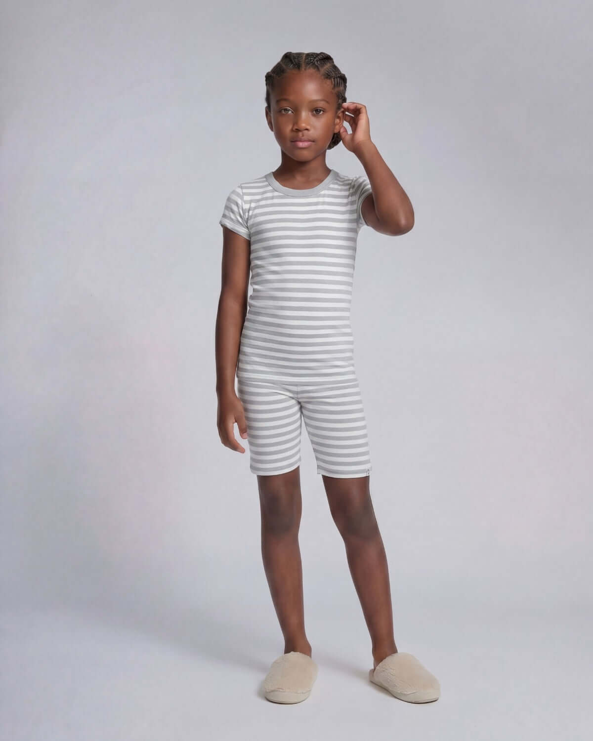 Young girl wearing a striped outfit on a plain background