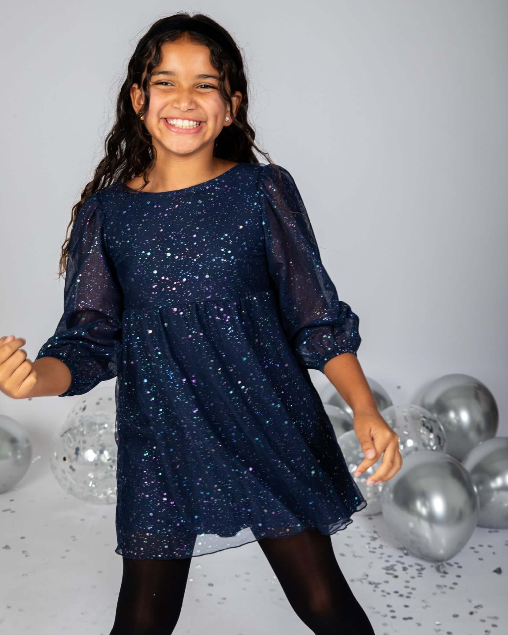 Girl wearing Navy Blue Chelsea Bow Dress, smiling with puffy sleeves and oversized bow, perfect for special occasions.