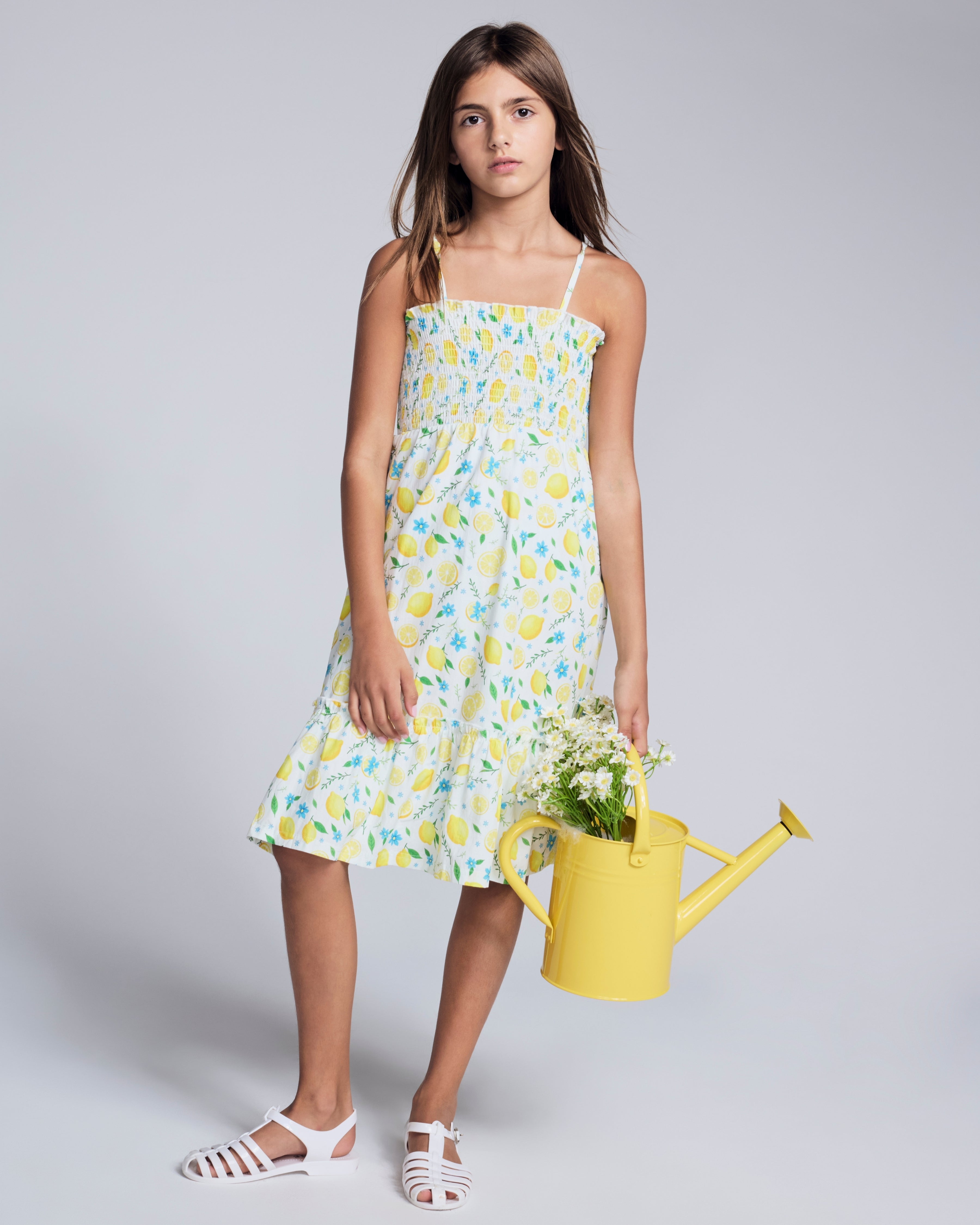 Lemon Zest Madison Dress worn by a girl holding a yellow watering can, designed for sunny days and outdoor adventures.