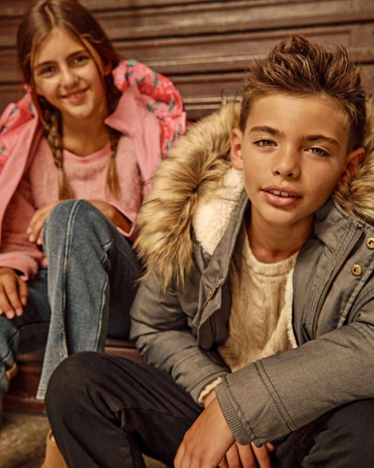 Two children wearing cozy coats, one in a Grey Denali Down Coat featuring a fur trim and sherpa lining.