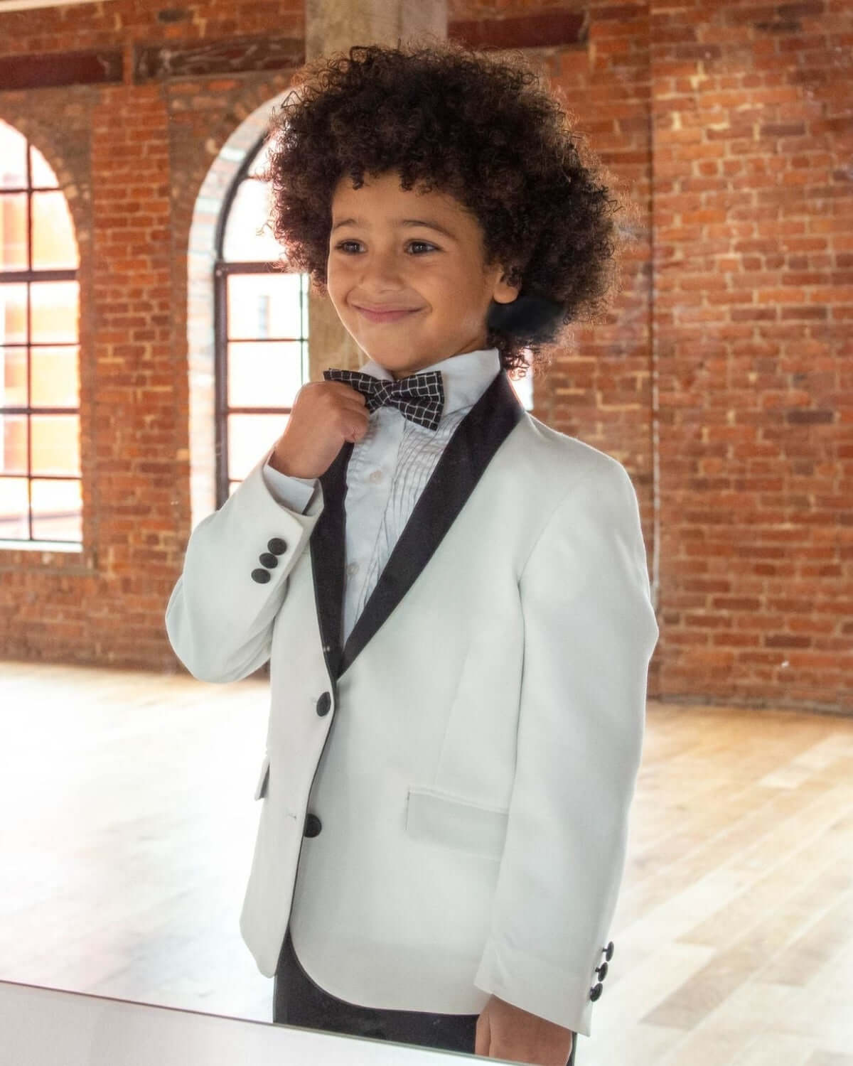Child wearing a White Tuxedo Suit Jacket with a satin collar and bow tie, perfect for formal events.