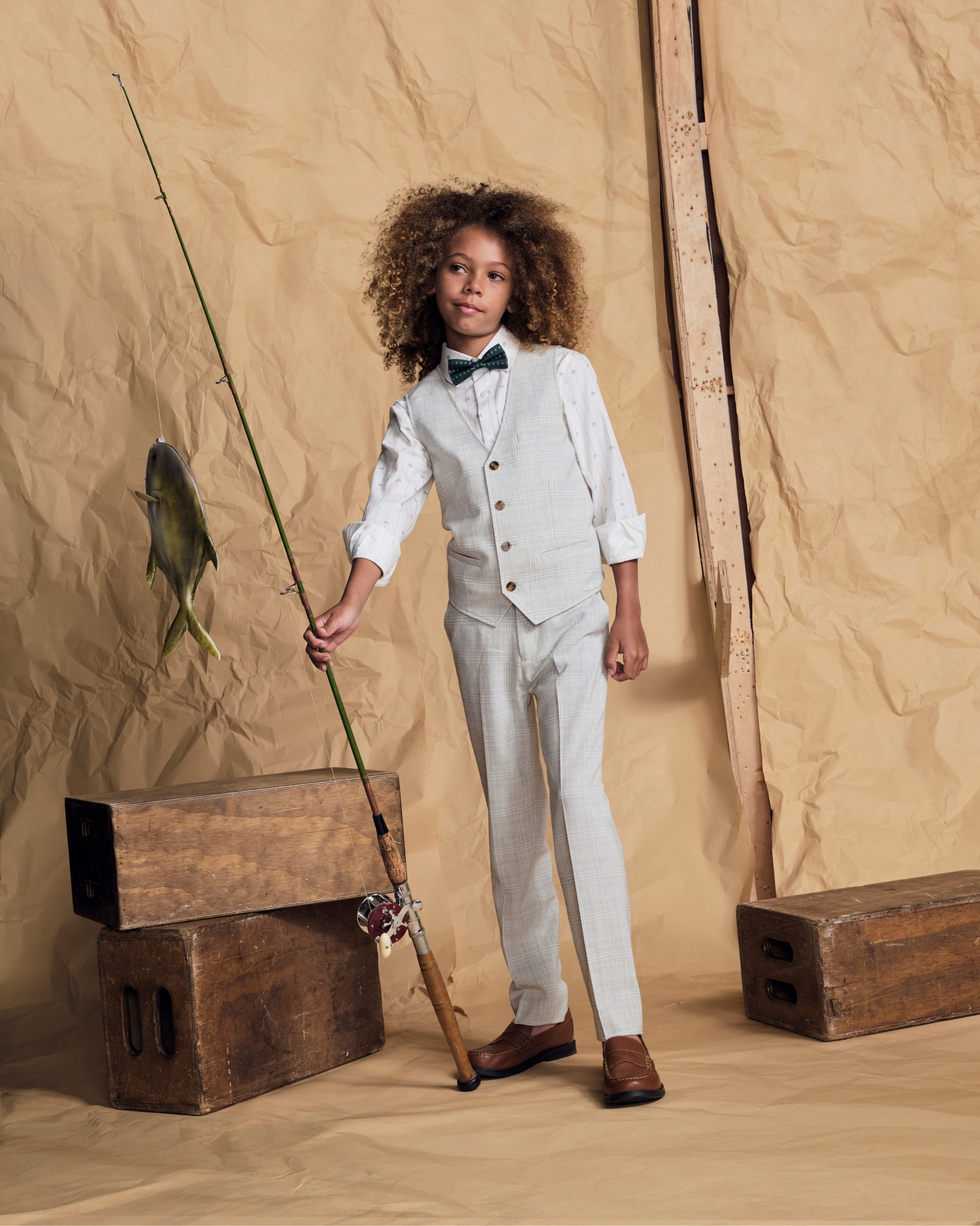 Linen Oceanside Plaid Stretchy Mod Suit Pant worn by a young boy posing with a fishing pole and a fish.