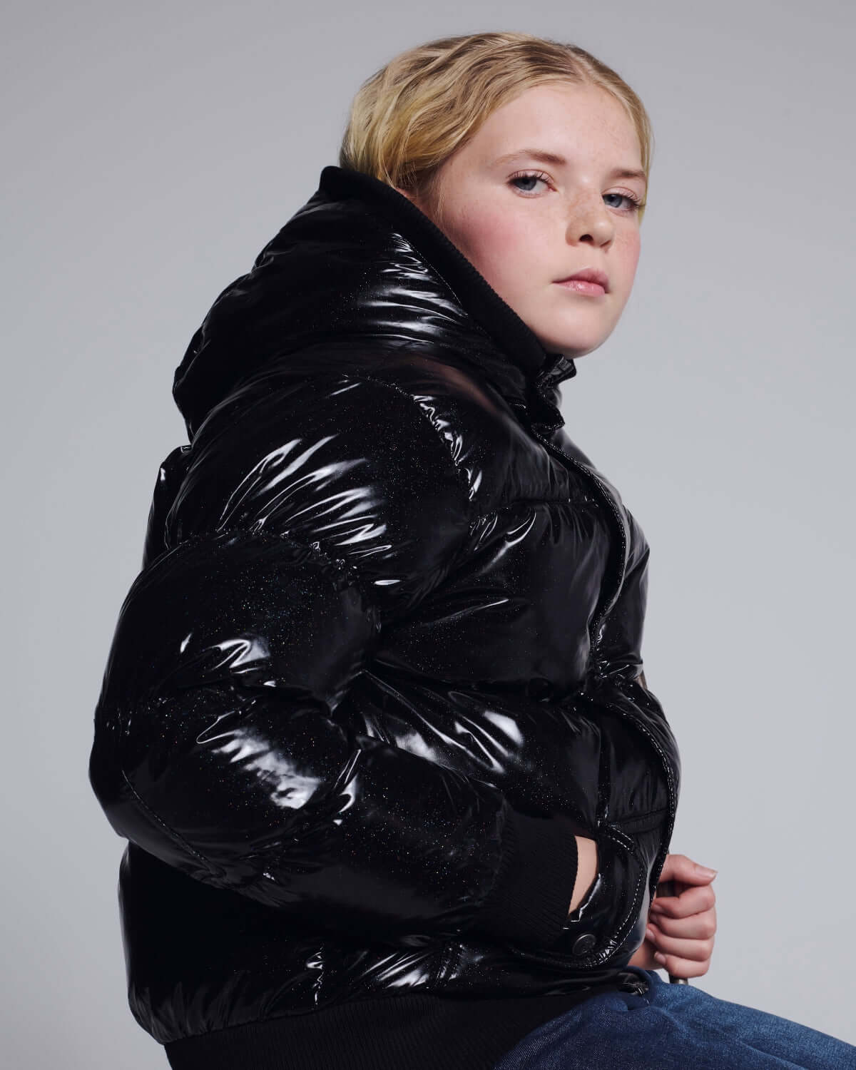 Glitter Black Slim Puffy Coat worn by a young girl, showcasing its shiny black design and cozy fit for stylish warmth.