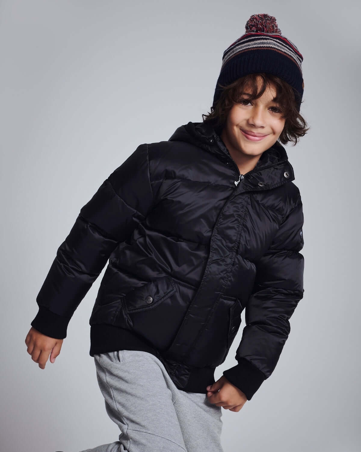 Boy wearing a Black Puffy Coat, featuring a durable shell and plush lining, perfect for winter adventures.