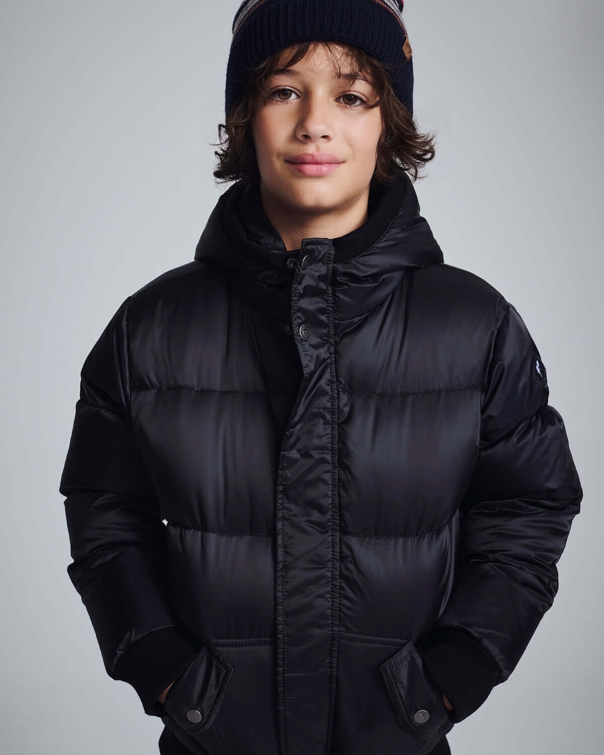 Boy wearing a Black Puffy Coat with a hood, featuring a stylish and warm design for winter activities.