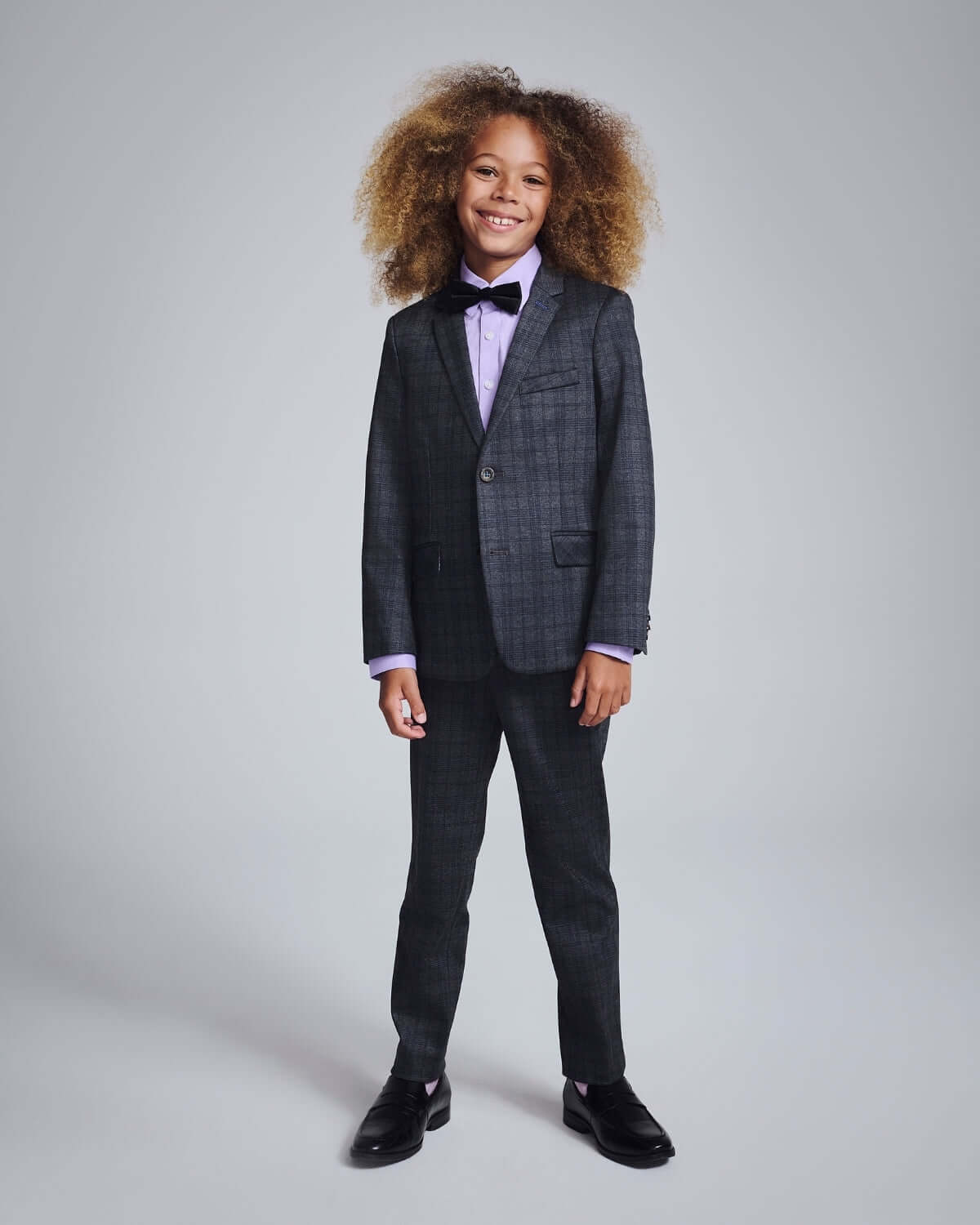 Gentleman's Plaid Stretchy Mod Suit modeled by a young boy with a stylish bow tie and curly hair.