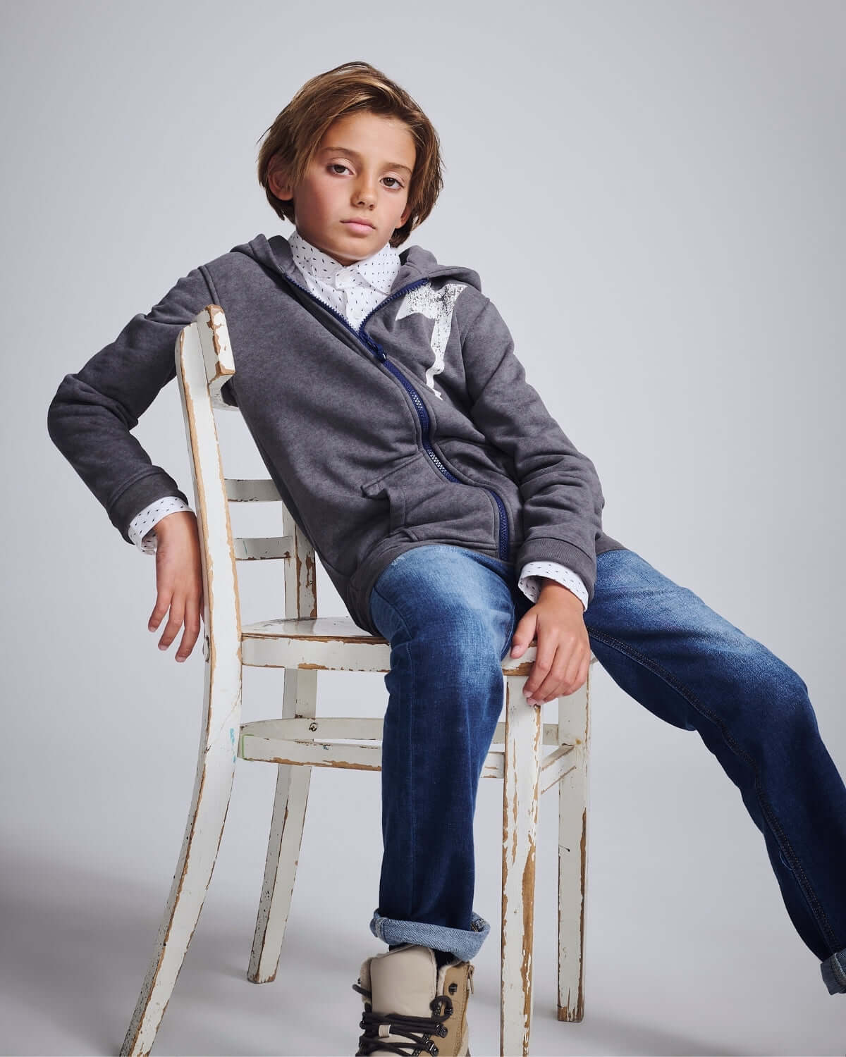 Medium Wash Slim Leg Denim worn by a stylish boy sitting on a chair, showcasing casual fashion.