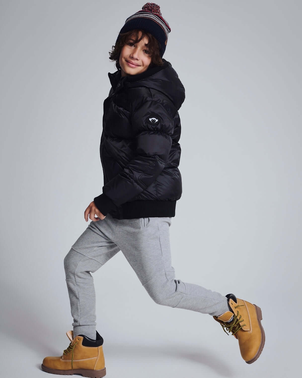 Child wearing Novelty Grey Heather Sideline Sweatpants with a black puffer jacket and yellow boots.