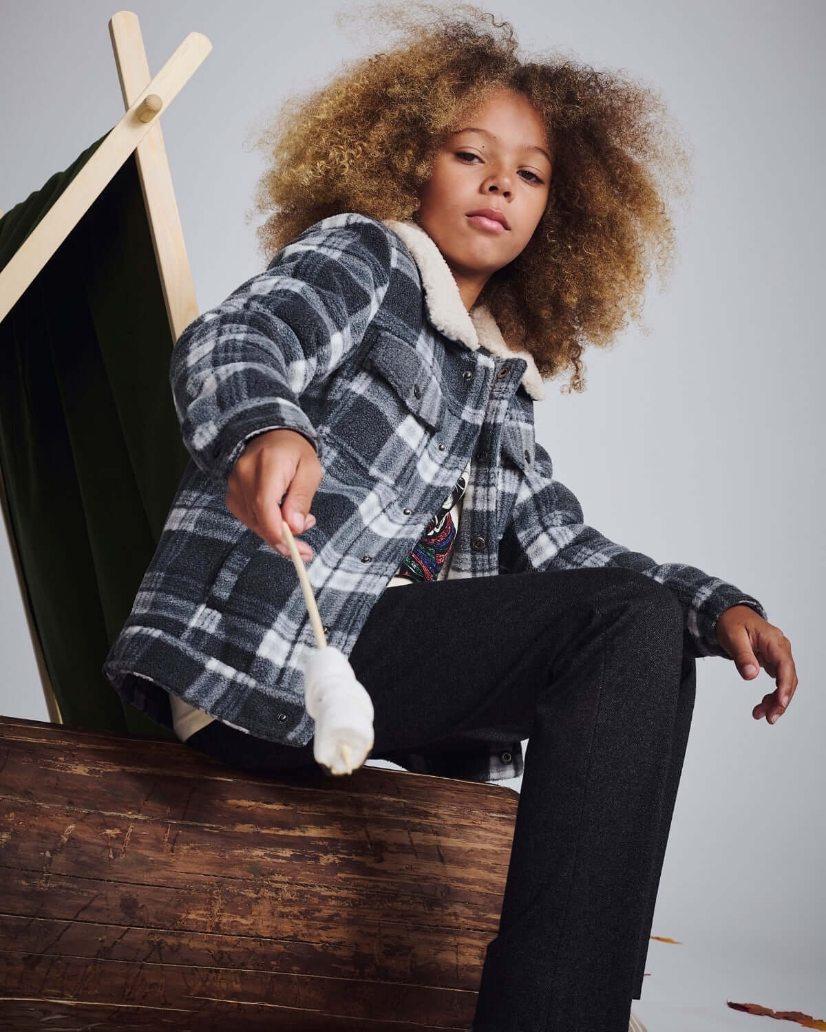 Kid wearing a cozy plaid jacket and Tweed Everyday Stretch Pants, enjoying a camping scene.