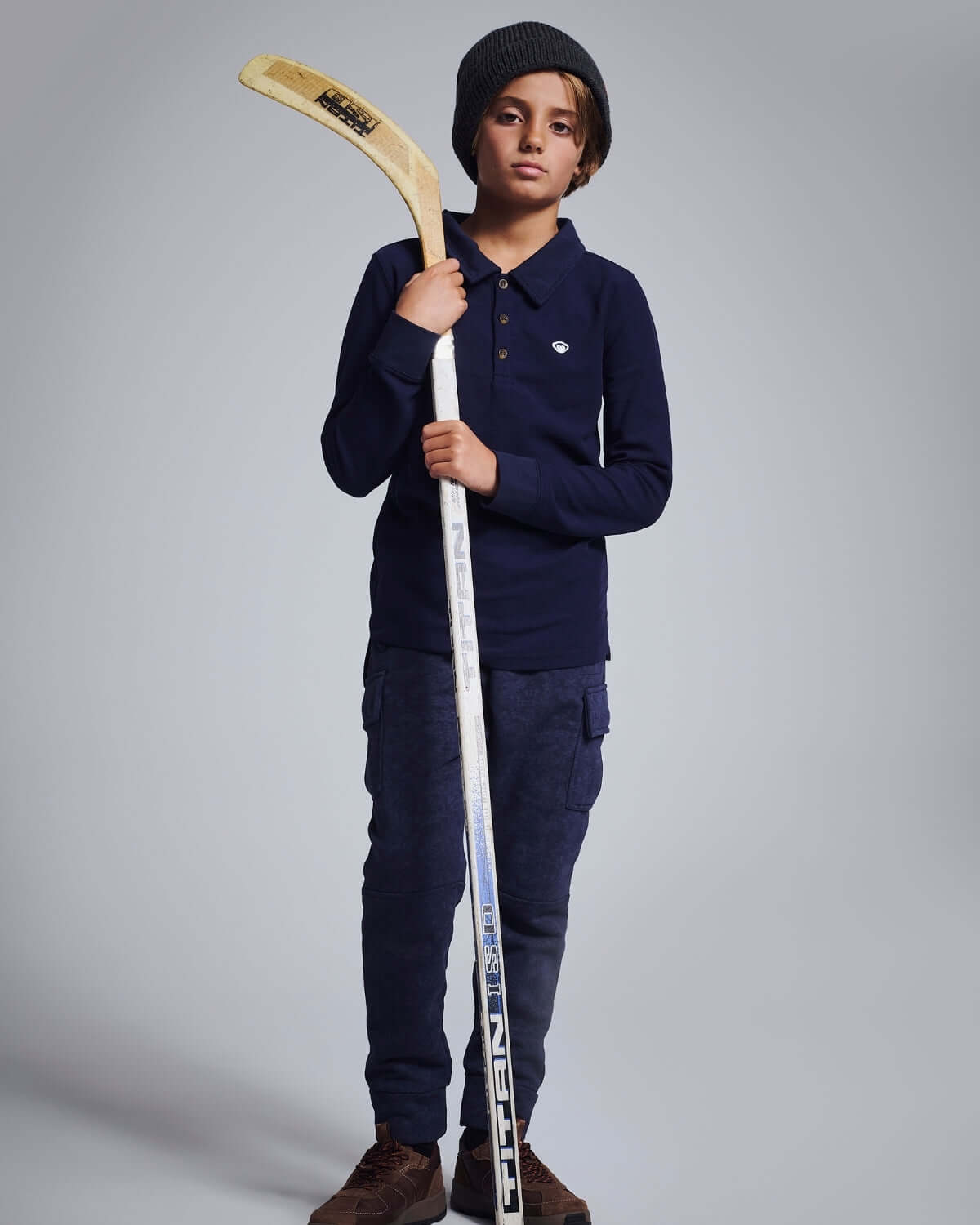 Child holding a hockey stick against a plain background
