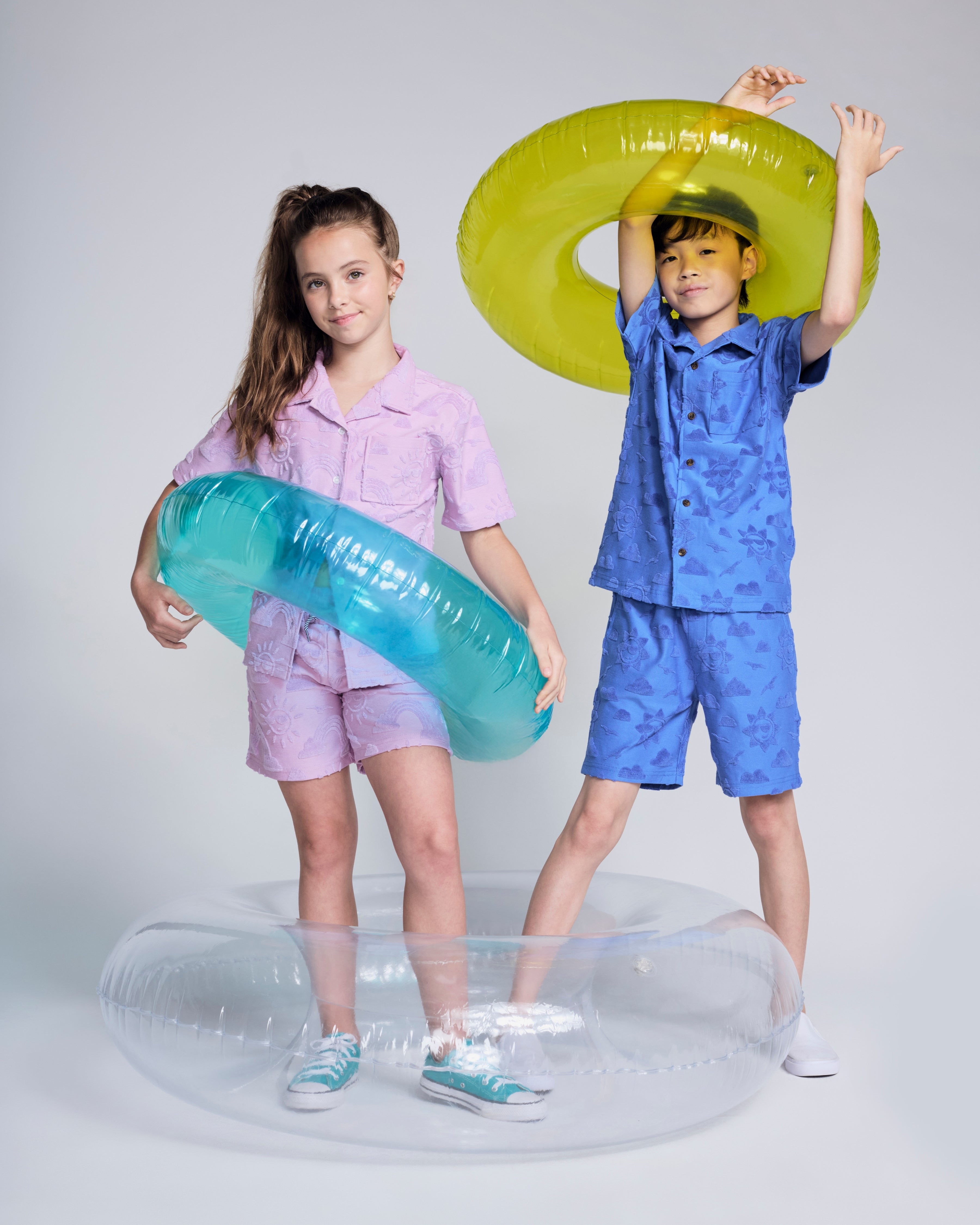 Children wearing the Sunny Days Lilac Resort Shirt and matching shorts with inflatable pool rings.