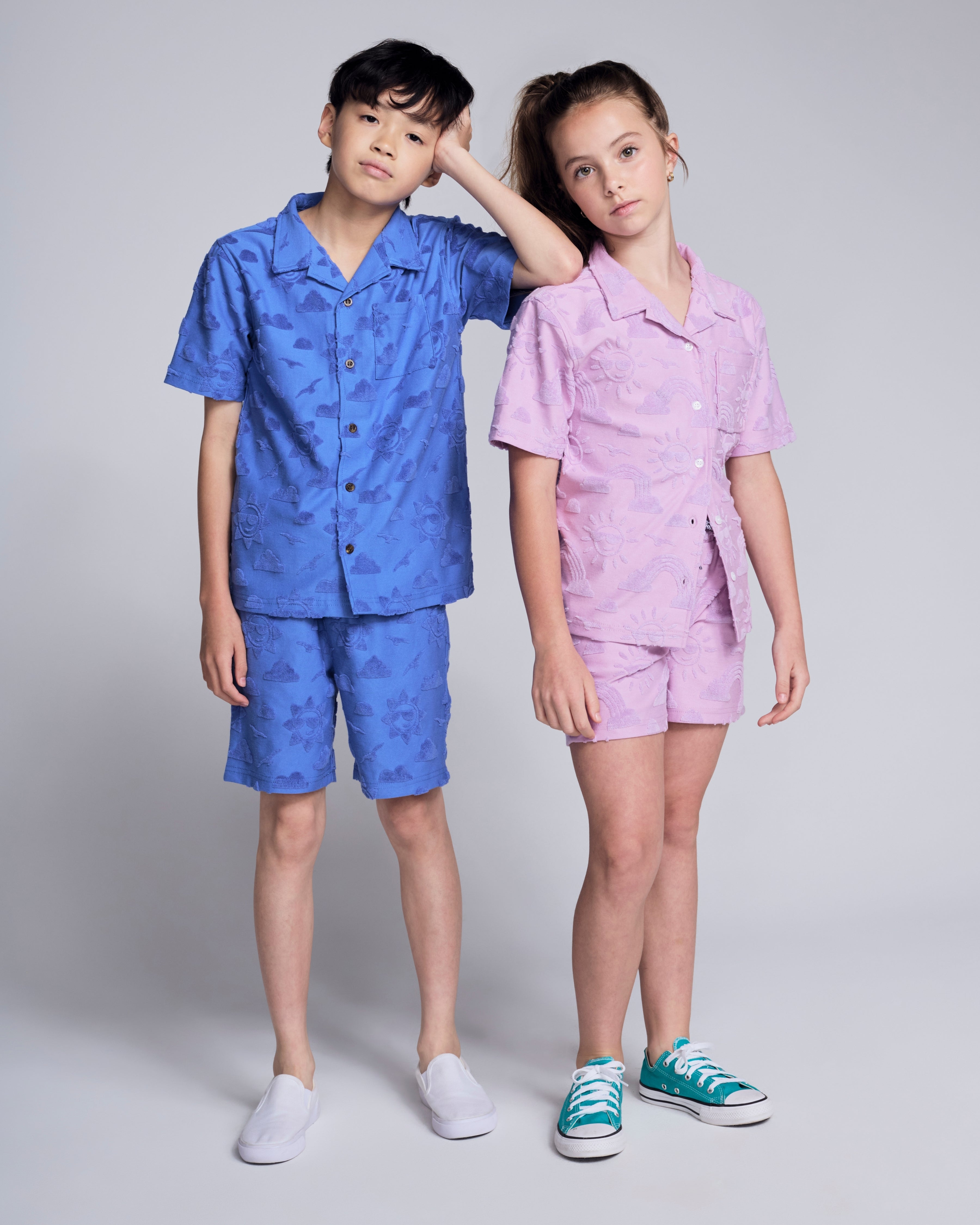 Two kids wearing Sunny Days Terry Lilac Resort Short and matching top in playful colors.