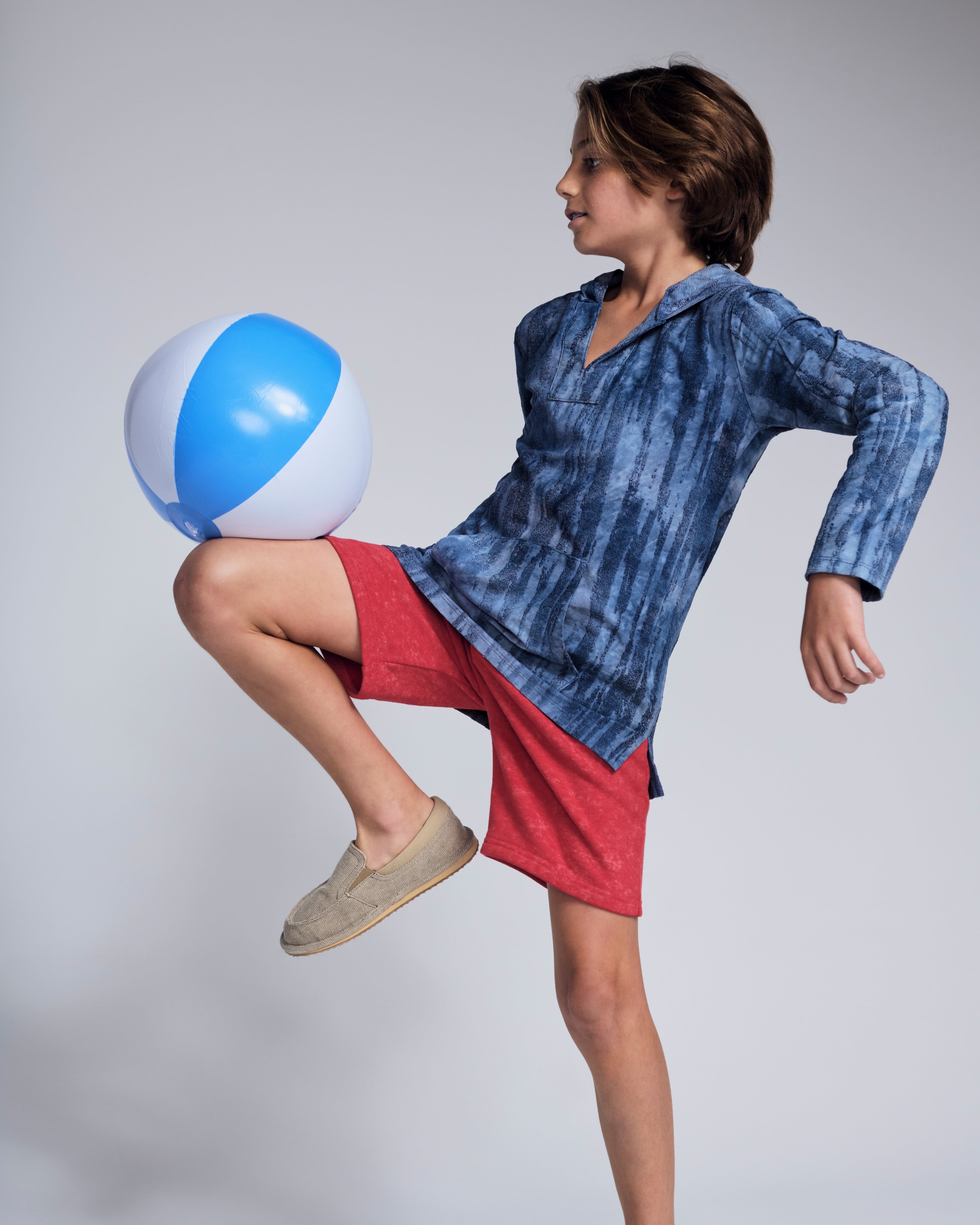 Boy playing with a beach ball while wearing Washed Red Preston Short and a blue hoodie.