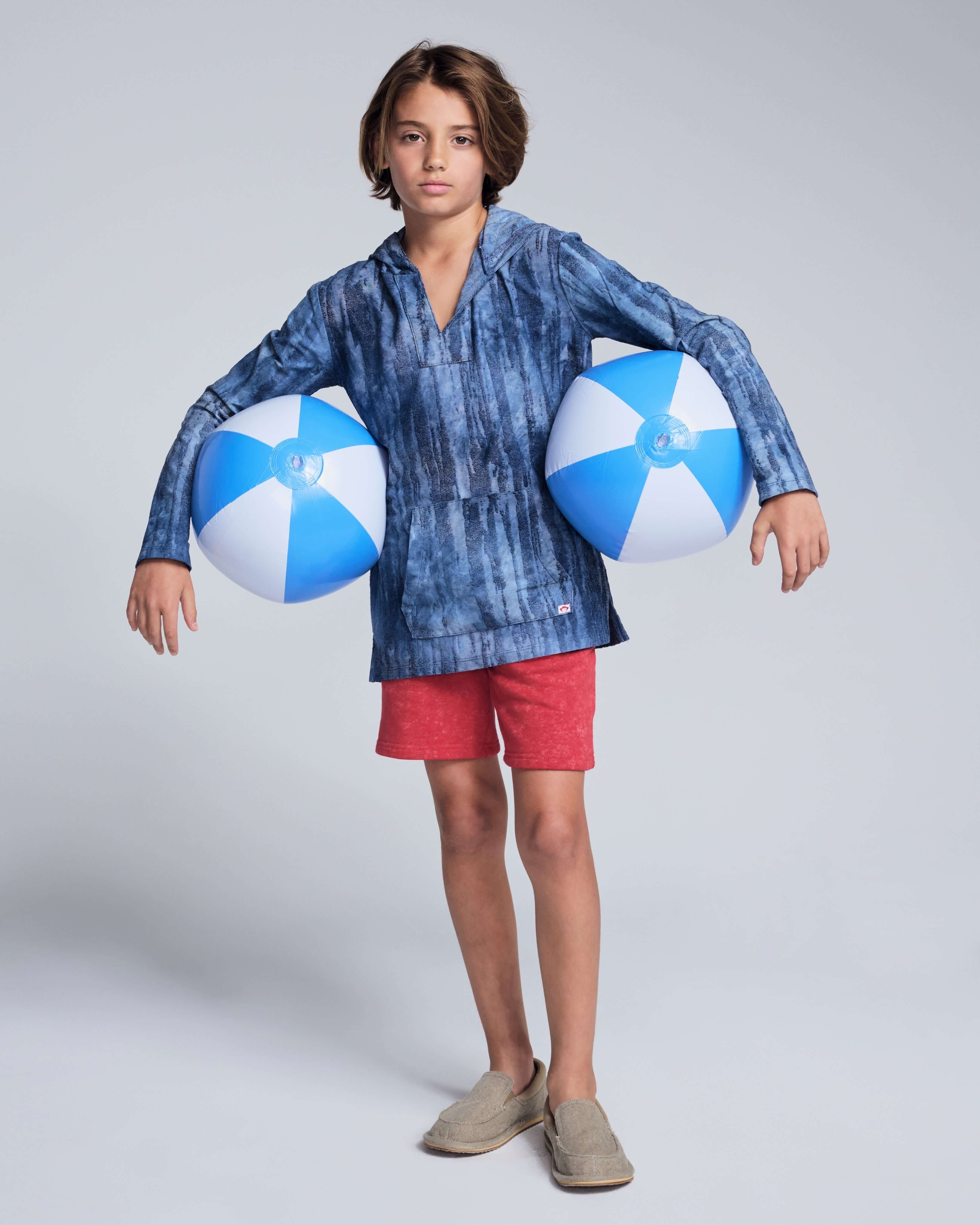 Boy wearing the Washed Red Preston Short and blue beach balls, ready for summer fun.