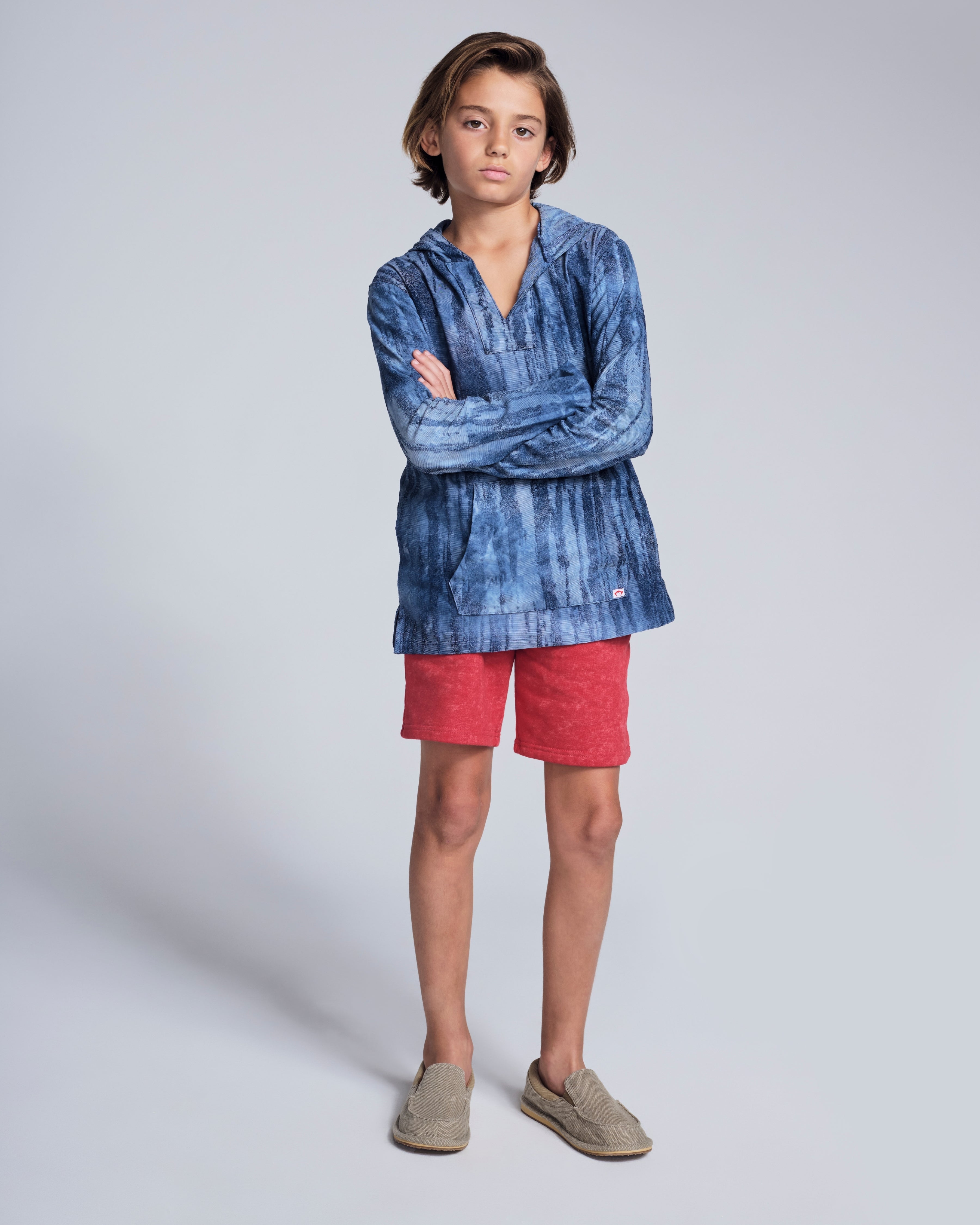 A child wearing a stylish Waterfall Terry Baja Pullover with red shorts, showcasing the unique tie dye design.