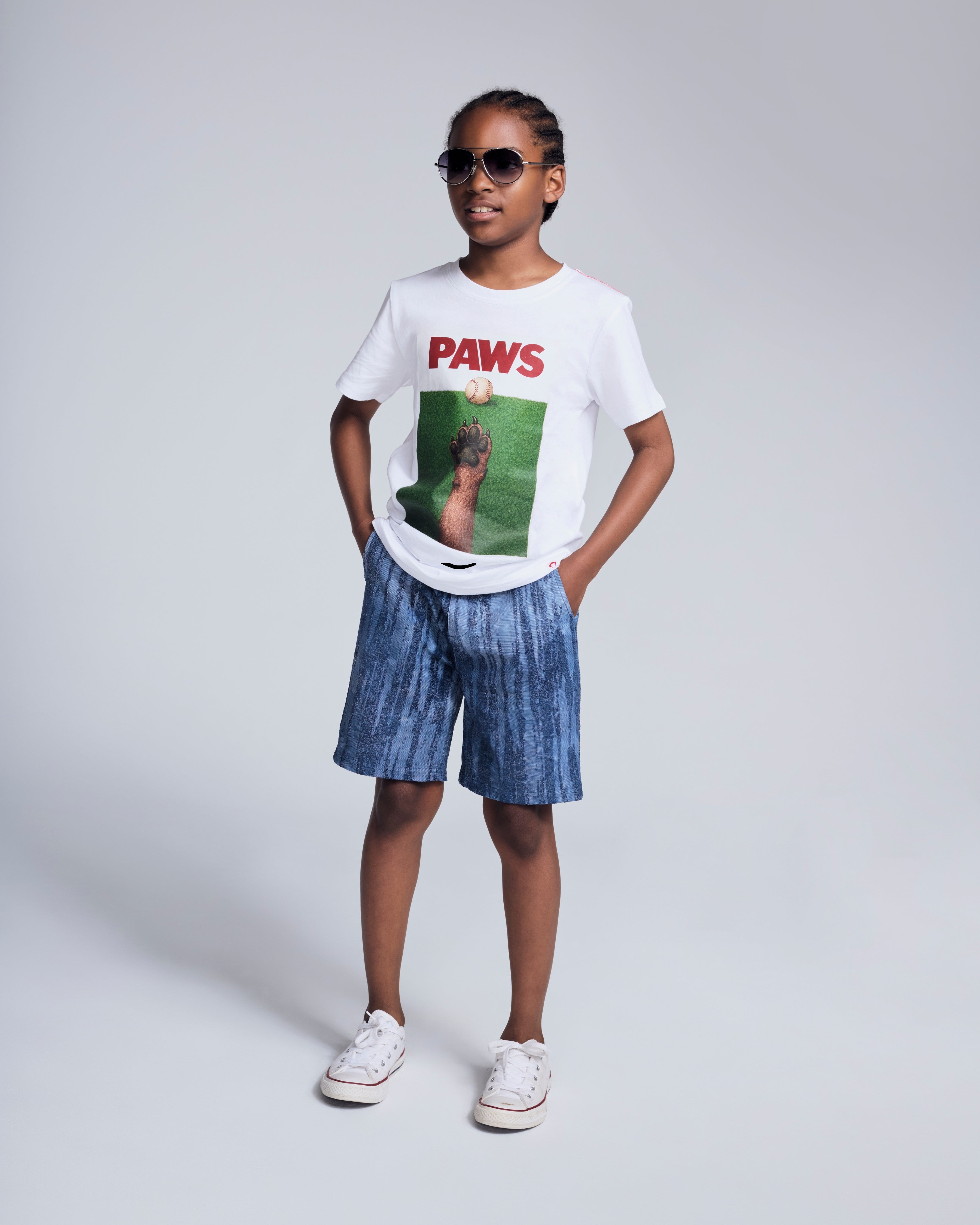 Child wearing Waterfall Preston Short and PAWS graphic tee, sunglasses, with a casual pose, ready for summer.