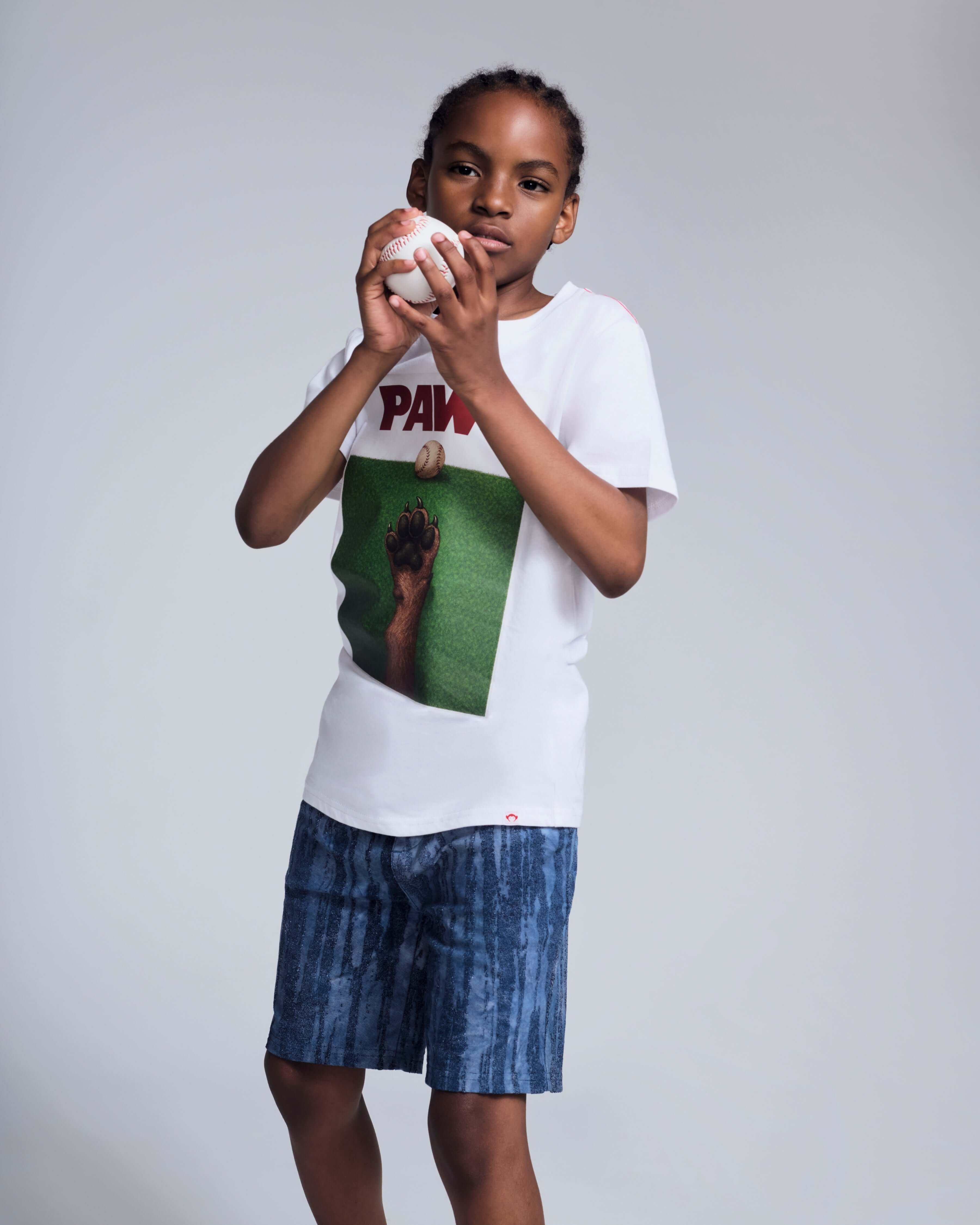 Child wearing a graphic tee and Waterfall Preston Short, ready to play with a baseball.
