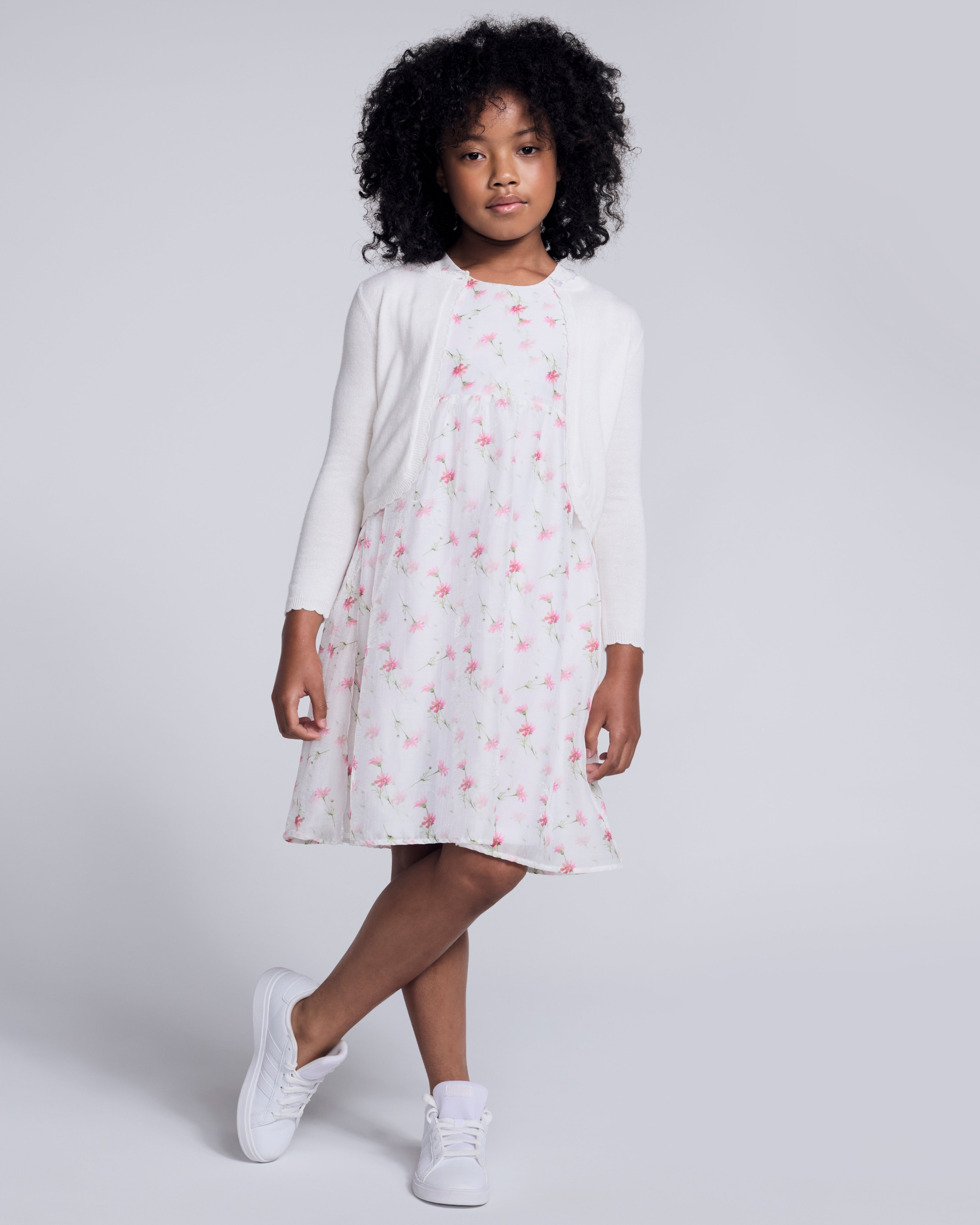 A girl wearing a White Bolero Cardigan over a floral dress, styled for spring and summer occasions.