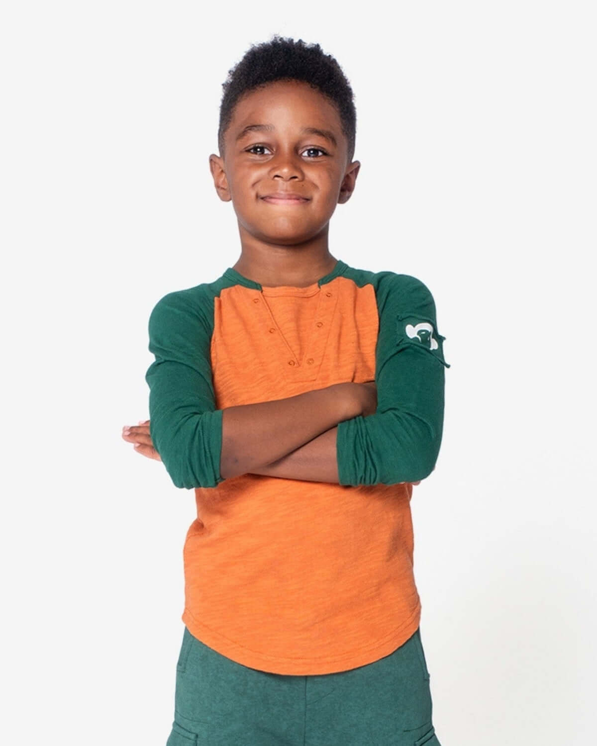 Young boy wearing a Terracotta Baseball Tee with green sleeves, perfect for casual outings or playtime.
