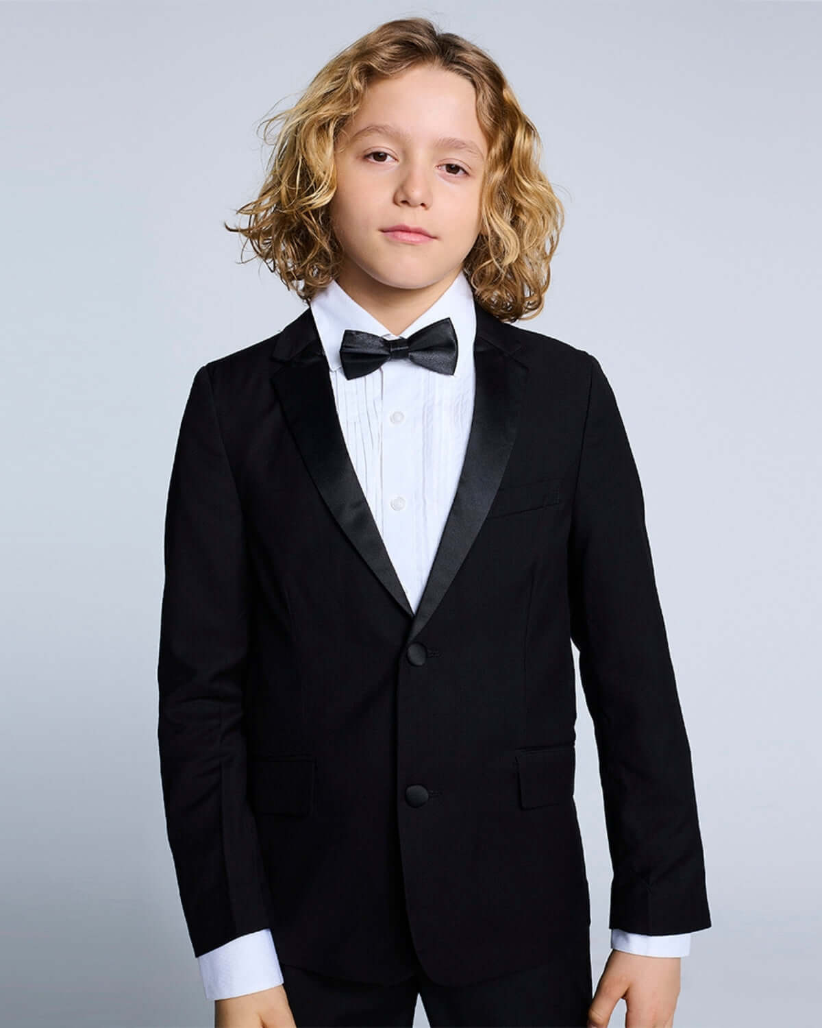 Boy wearing a tuxedo from the Tuxedo Suit Bundle 3-Piece Set, featuring a sleek jacket, bow tie, and dress shirt.